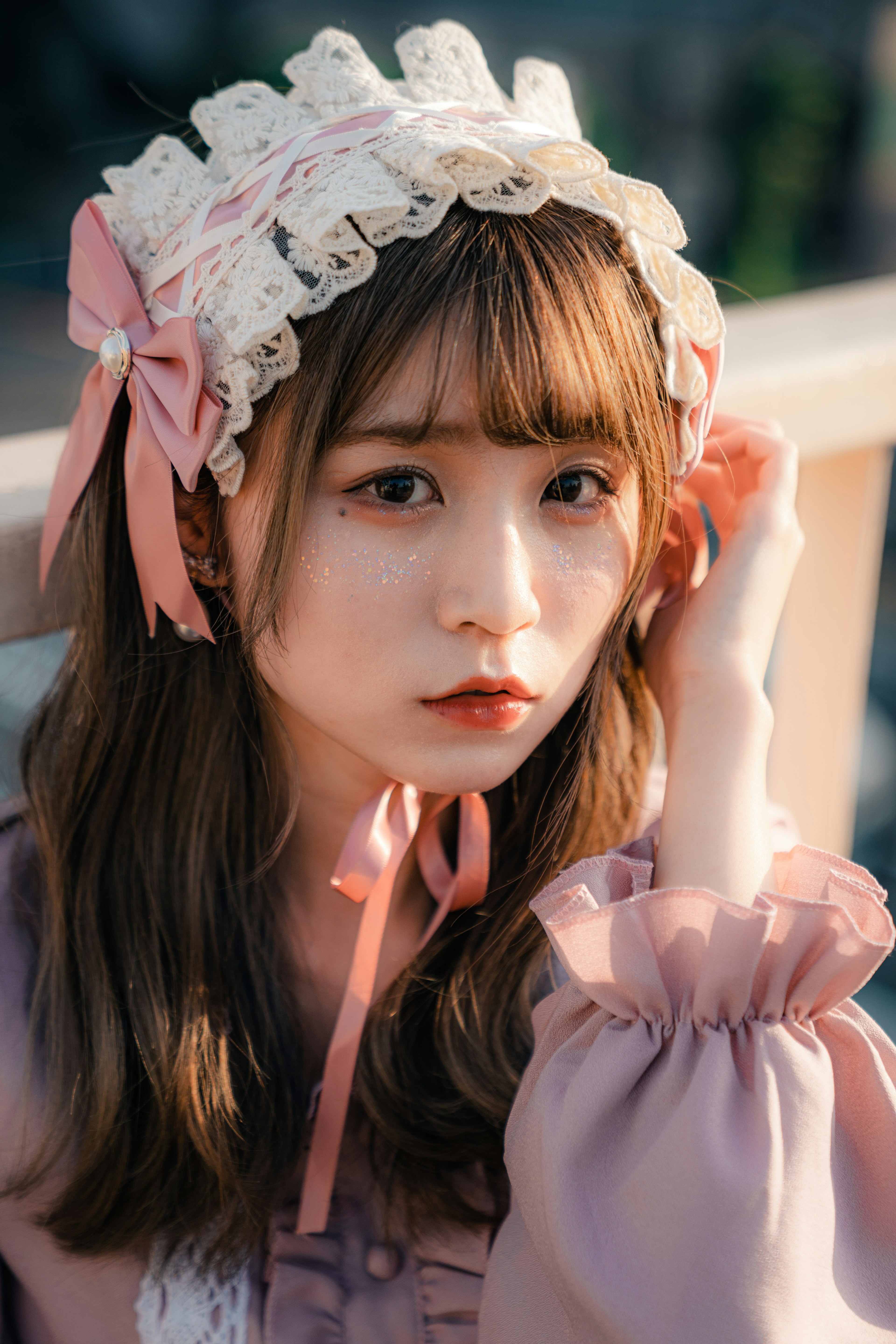 A young girl wearing a soft-colored outfit gazes at the camera while wearing a ribbon-adorned hat