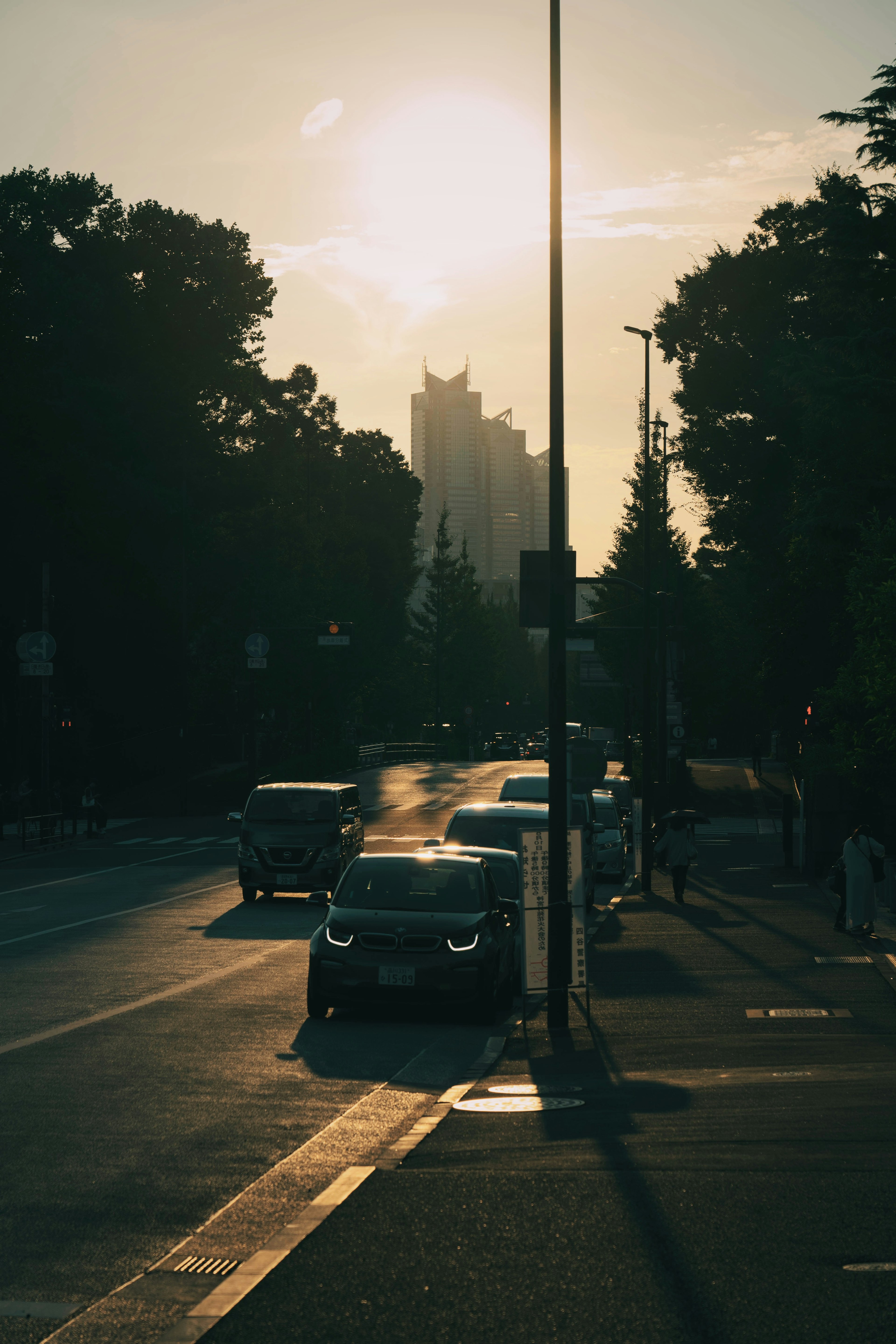 Silueta de coches en una calle con el atardecer de fondo