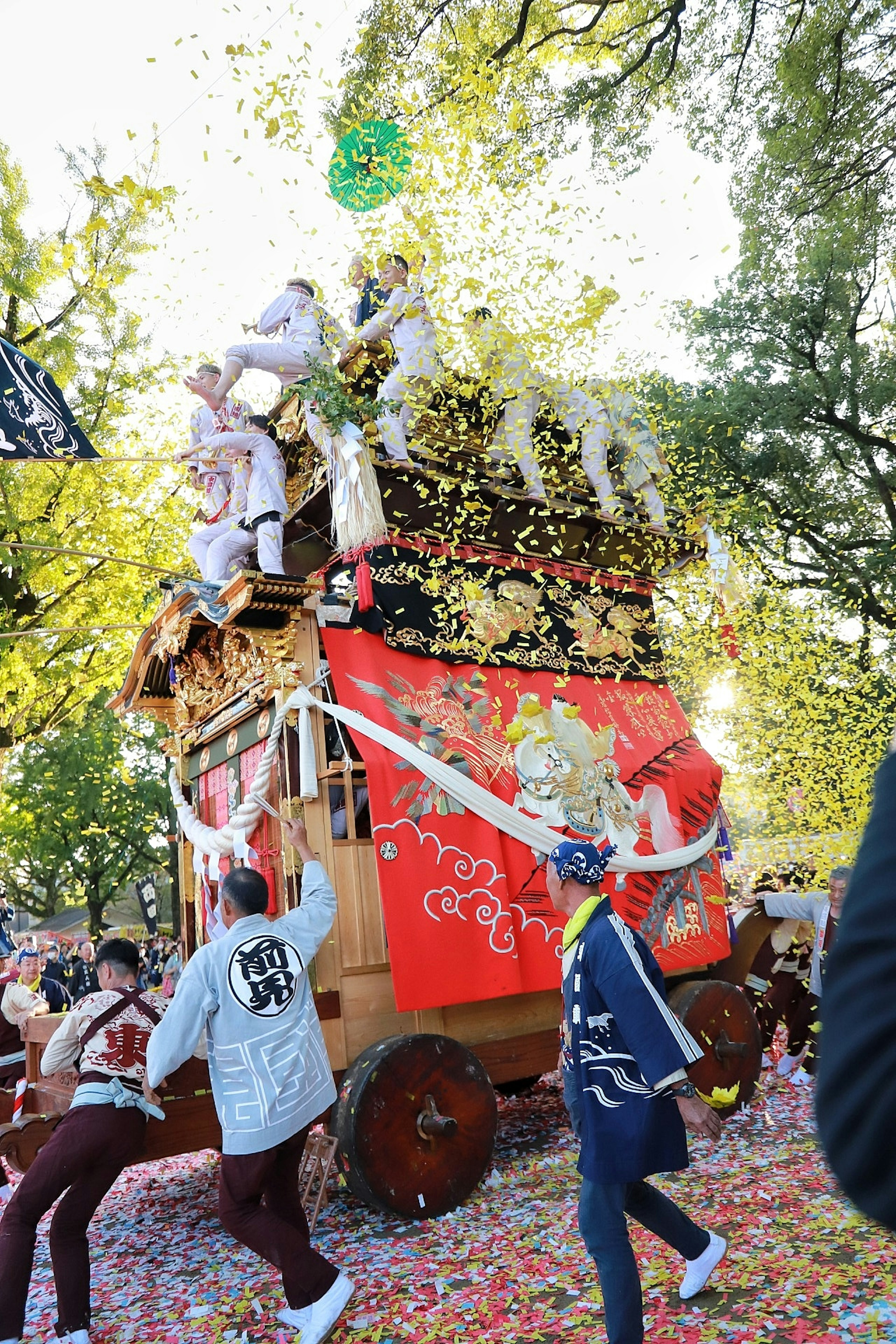 祭りの山車が花びらの中で飾られている様子 参加者が衣装を着て山車の周りで踊っている