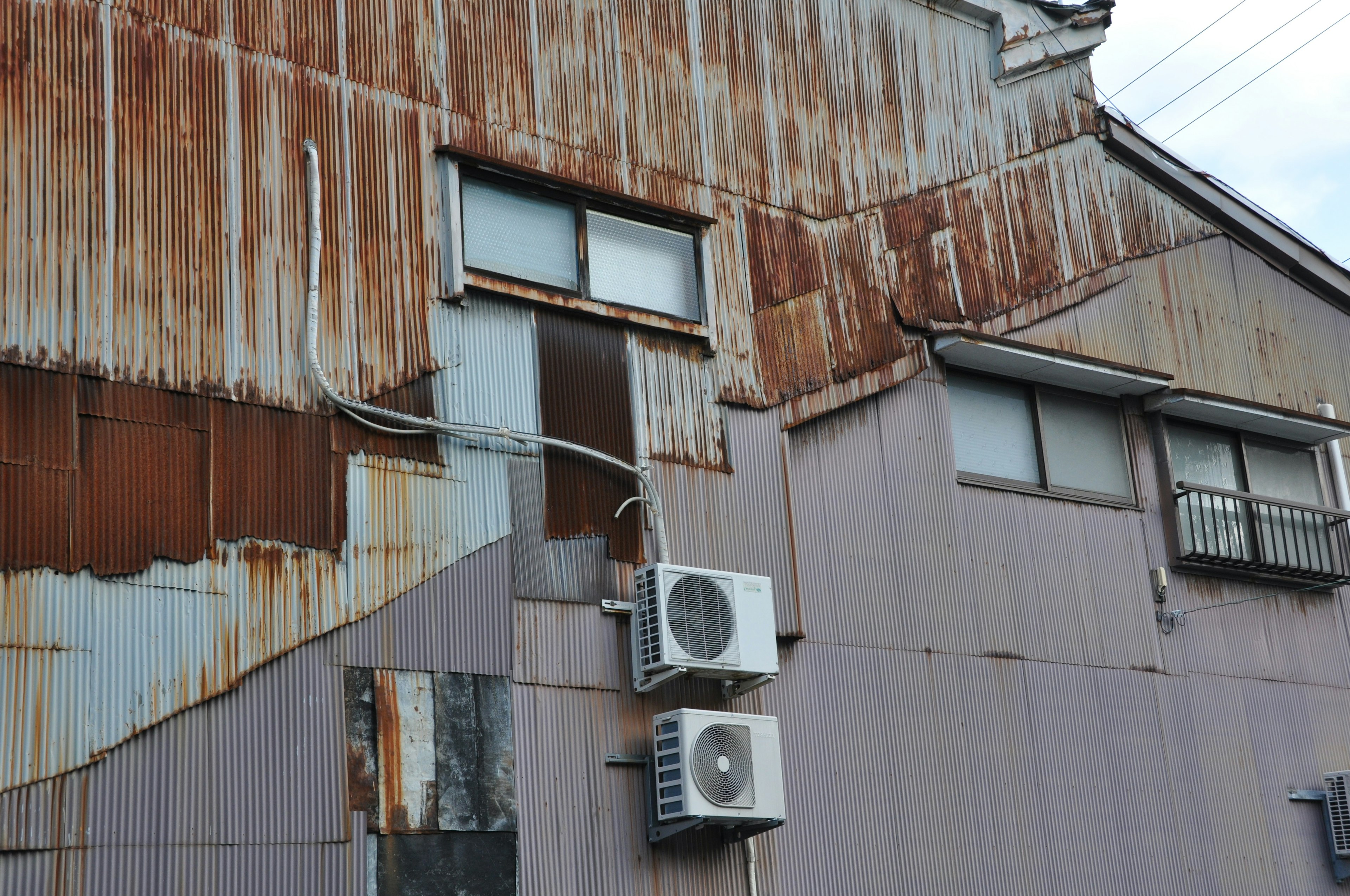 Parte di un edificio con rivestimento in metallo arrugginito e unità di condizionamento