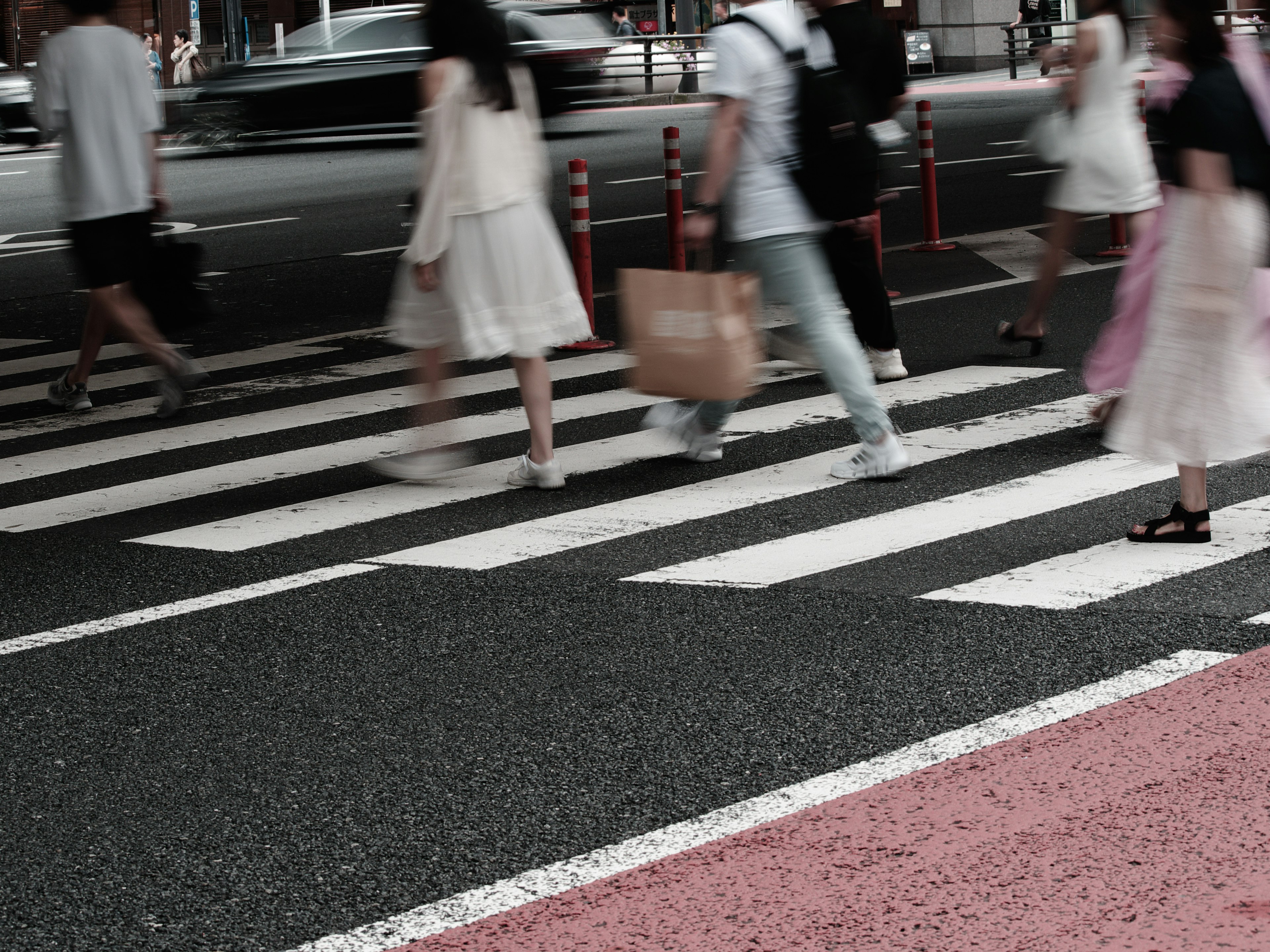 Crowd of people walking at a crosswalk featuring white stripes and a red line