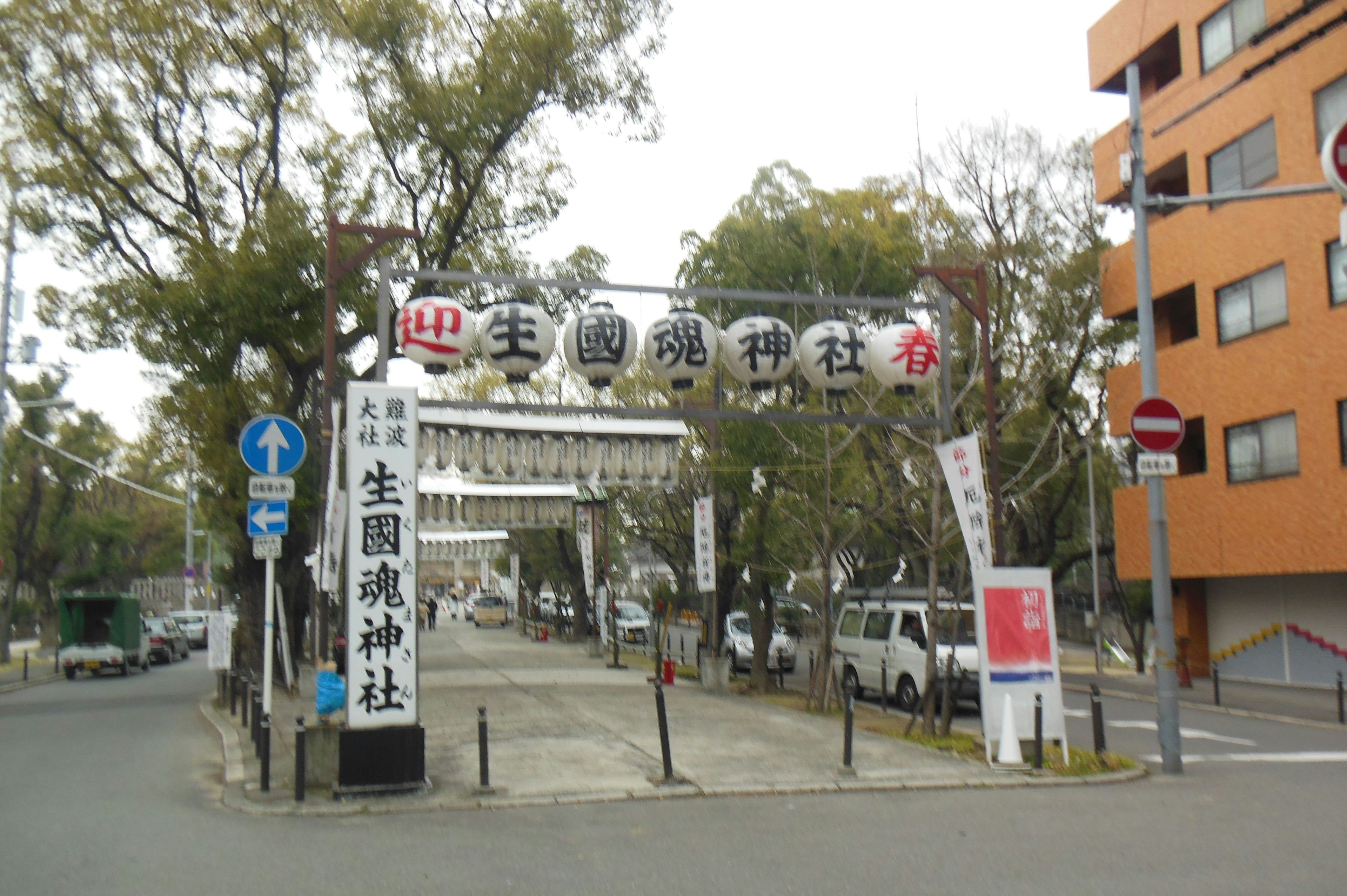 Image of the entrance to Ikukunitama Shrine with surrounding trees and buildings