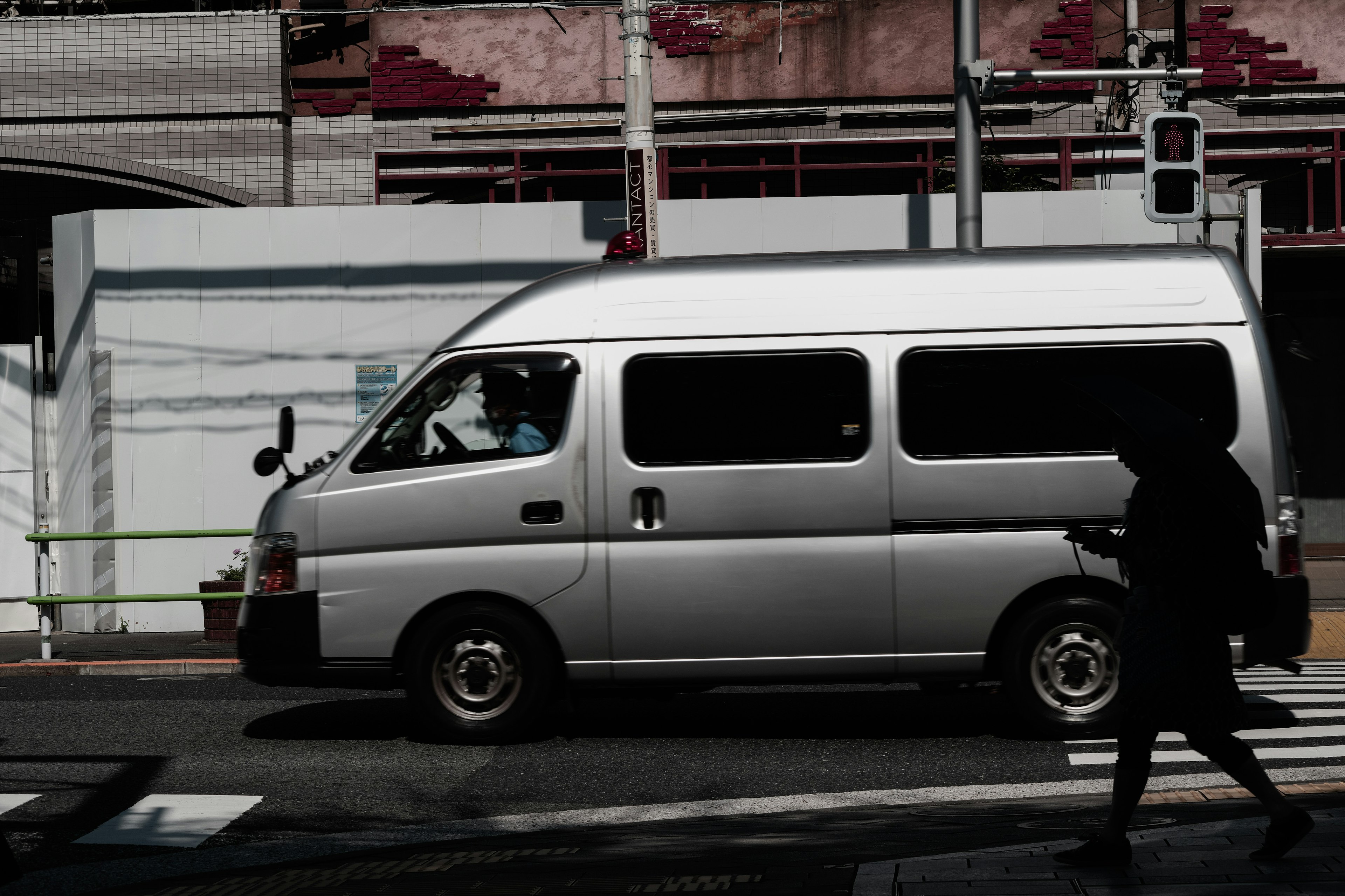 A silver van driving on the street with a pedestrian crossing