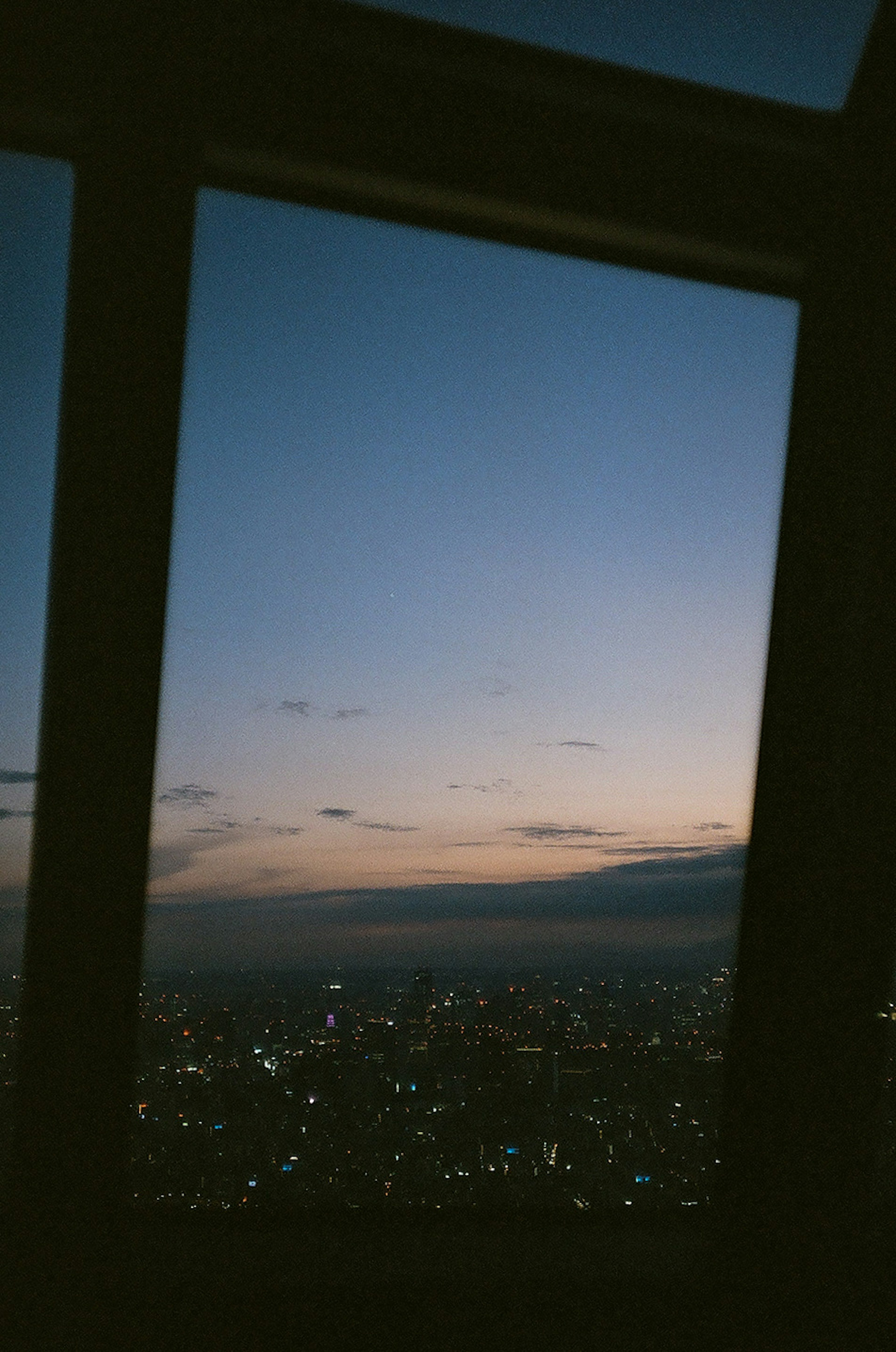 View of a city skyline at twilight through a window with a gradient sky