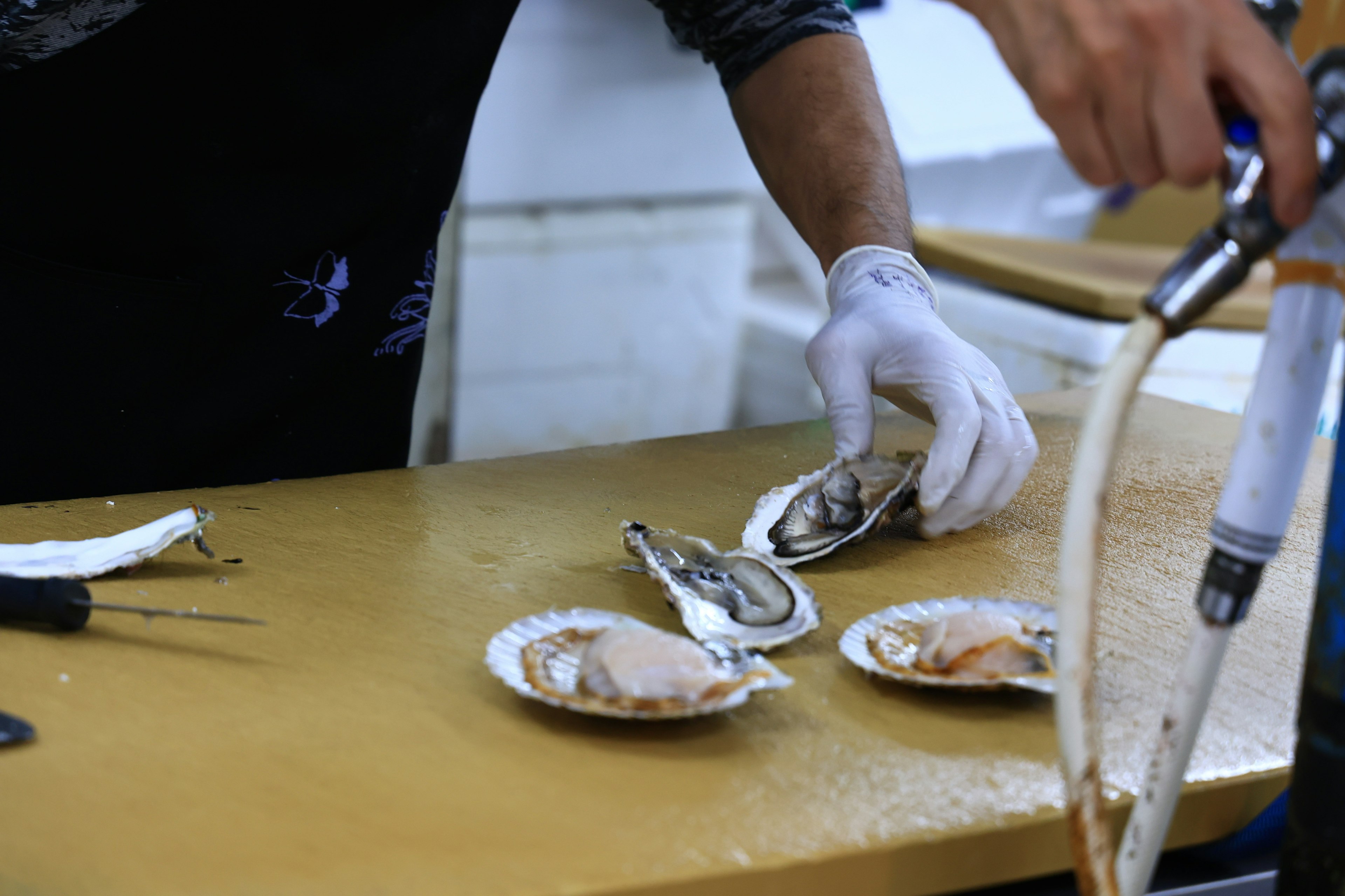 Chef ouvrant des huîtres fraîches avec des assiettes d'huîtres sur une table en bois