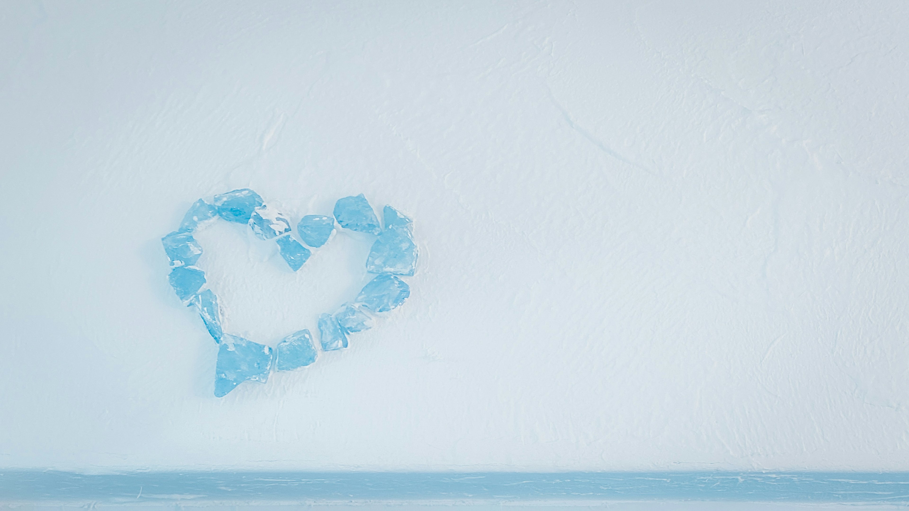 A heart shape made of blue ice against a white background