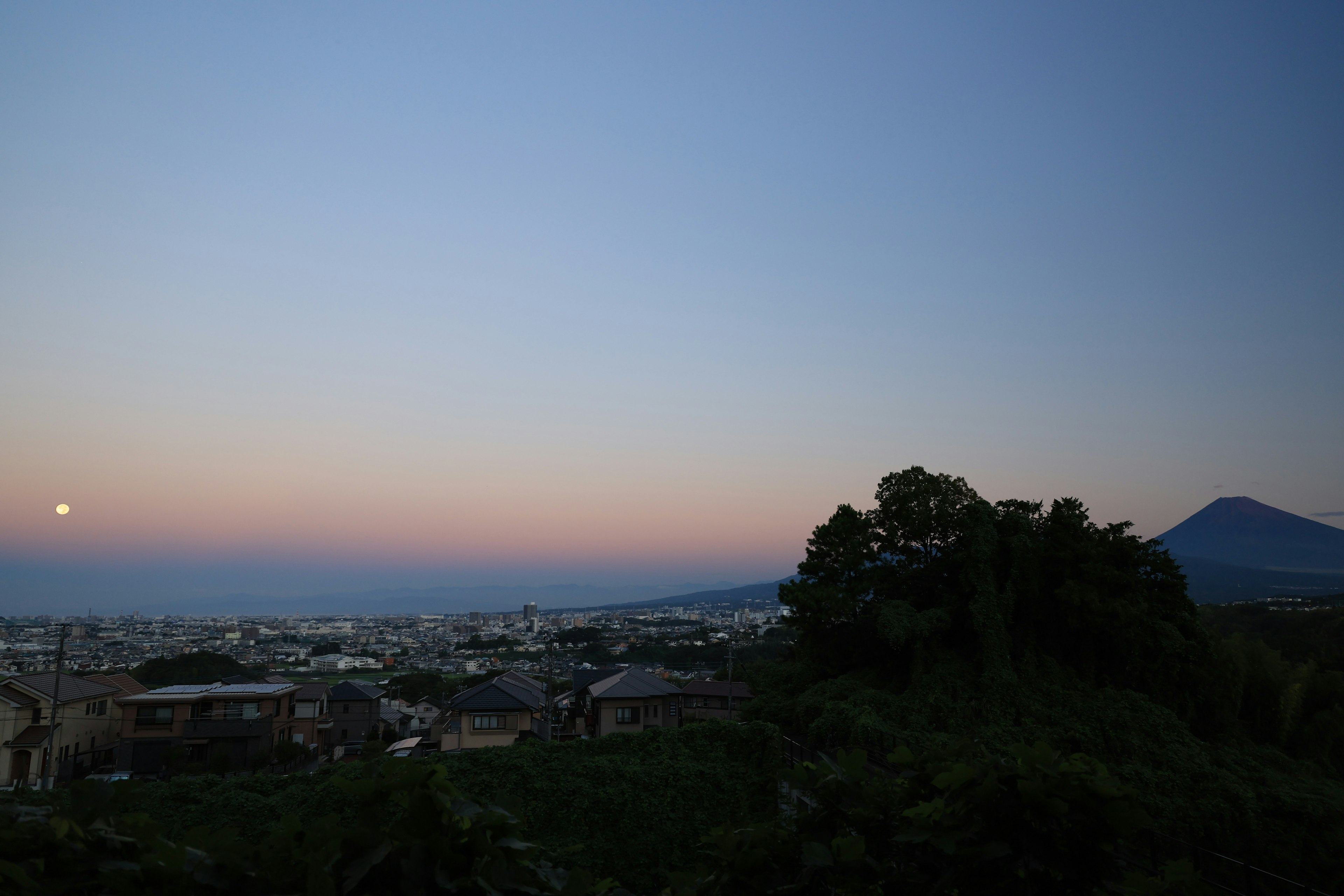 Scenic view of a town at dusk with a rising moon