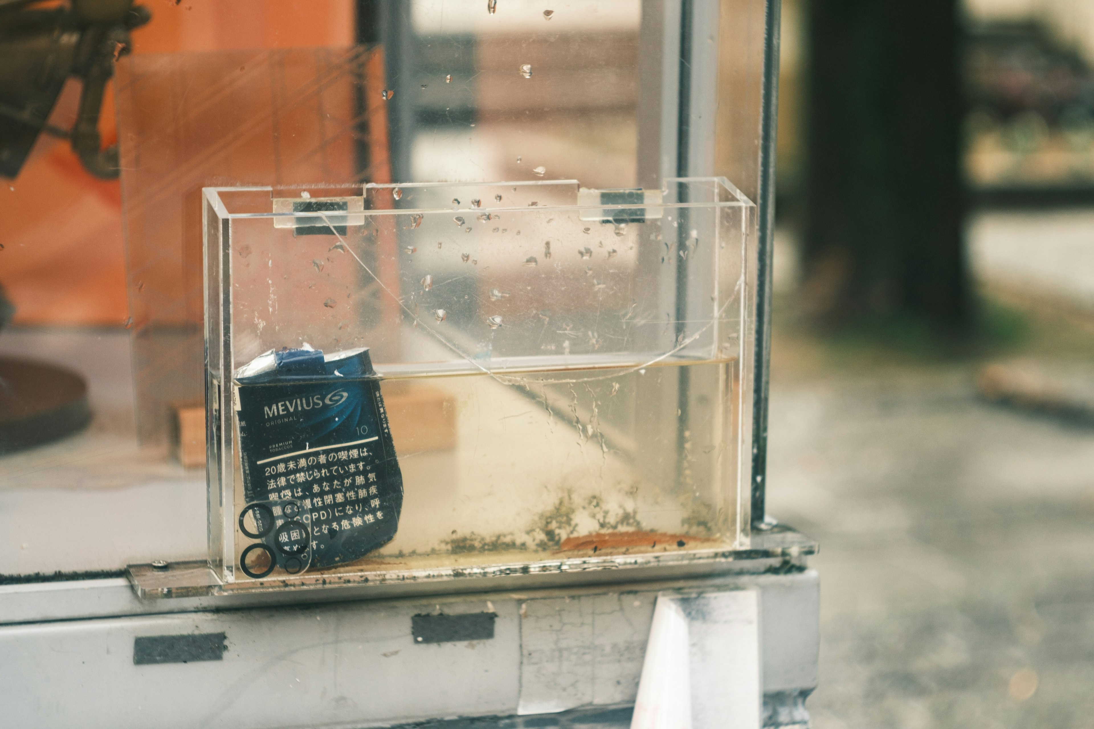 An old calculator submerged in a water tank with a blurred background