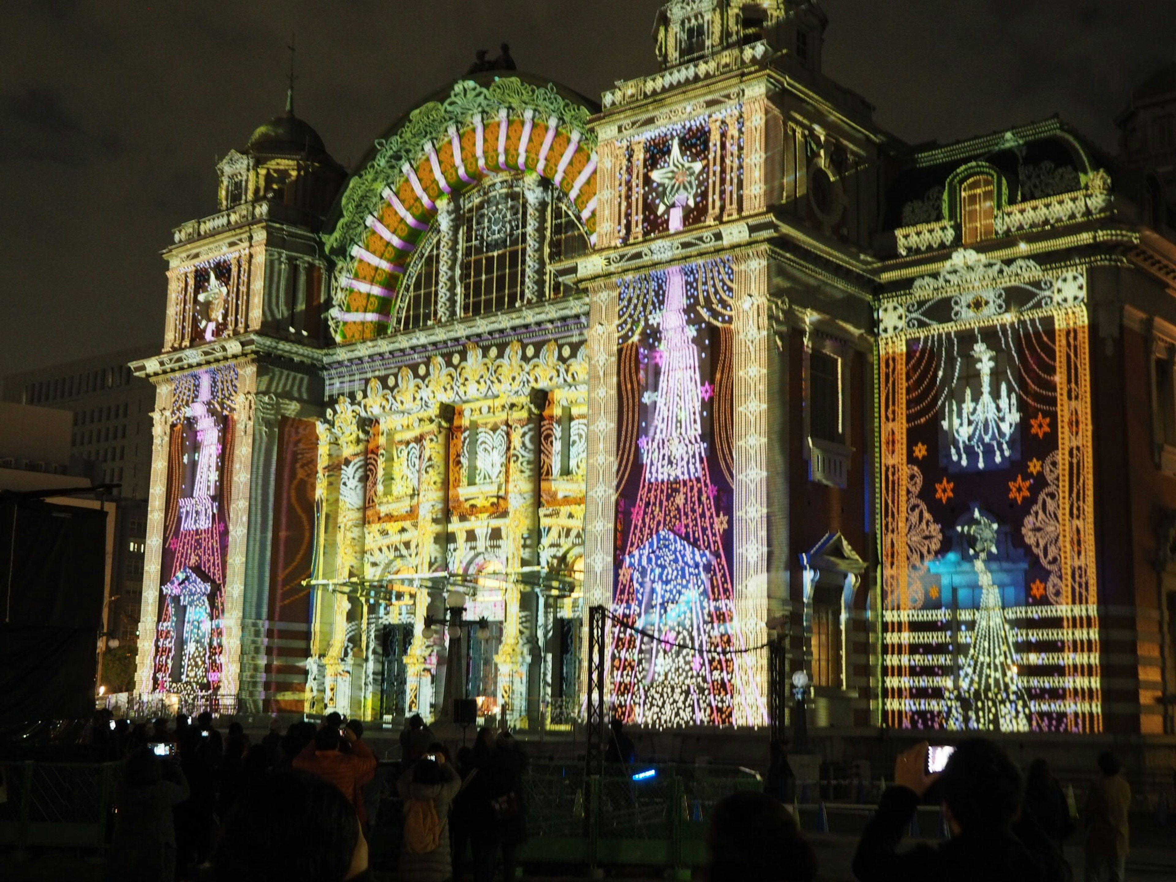 Schöne Fassade eines historischen Gebäudes, das nachts mit bunten Lichtern beleuchtet ist