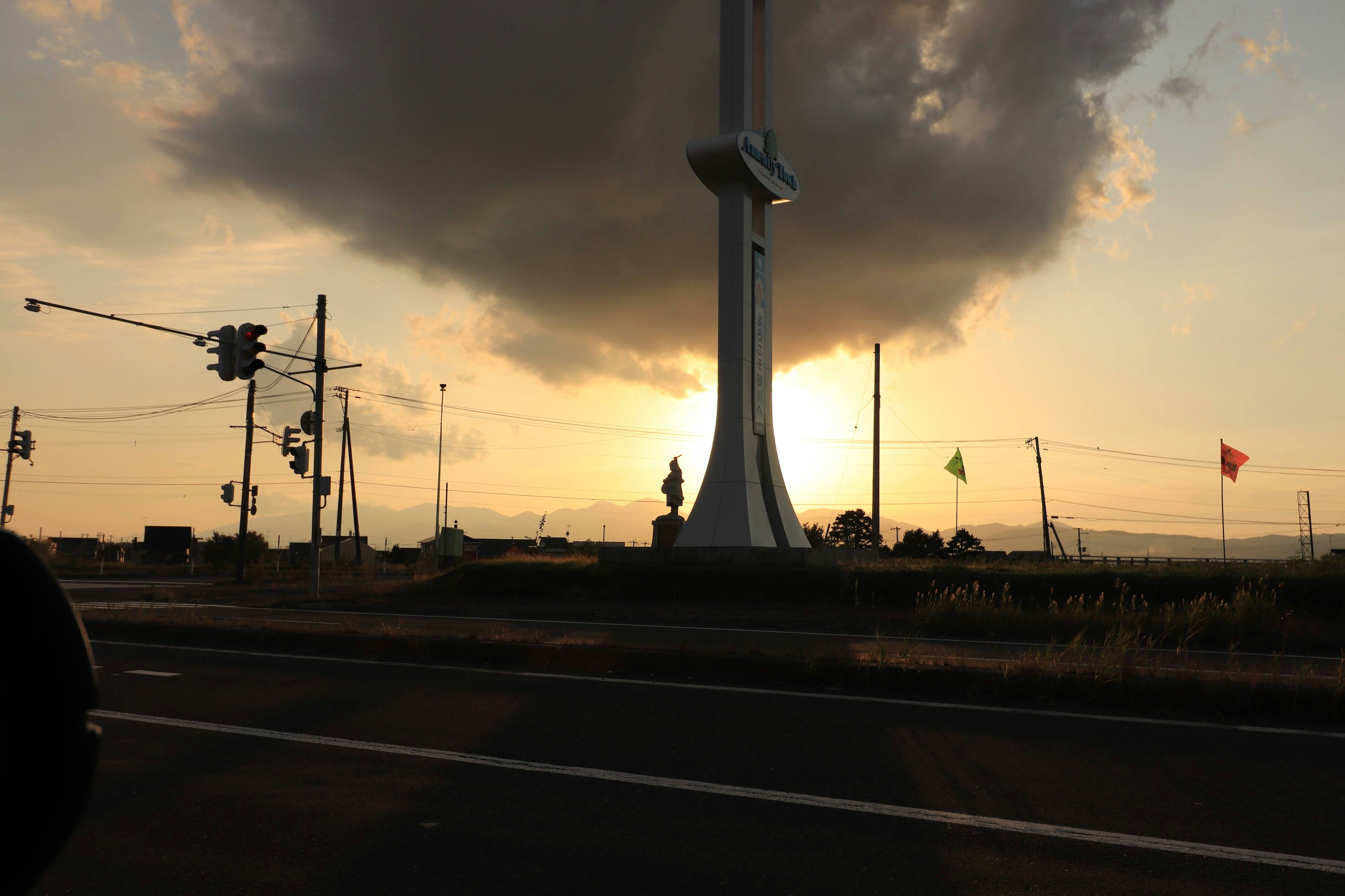 Silhouette eines großen Turms vor einem Sonnenuntergangshimmel mit Wolken und Verkehrsampeln