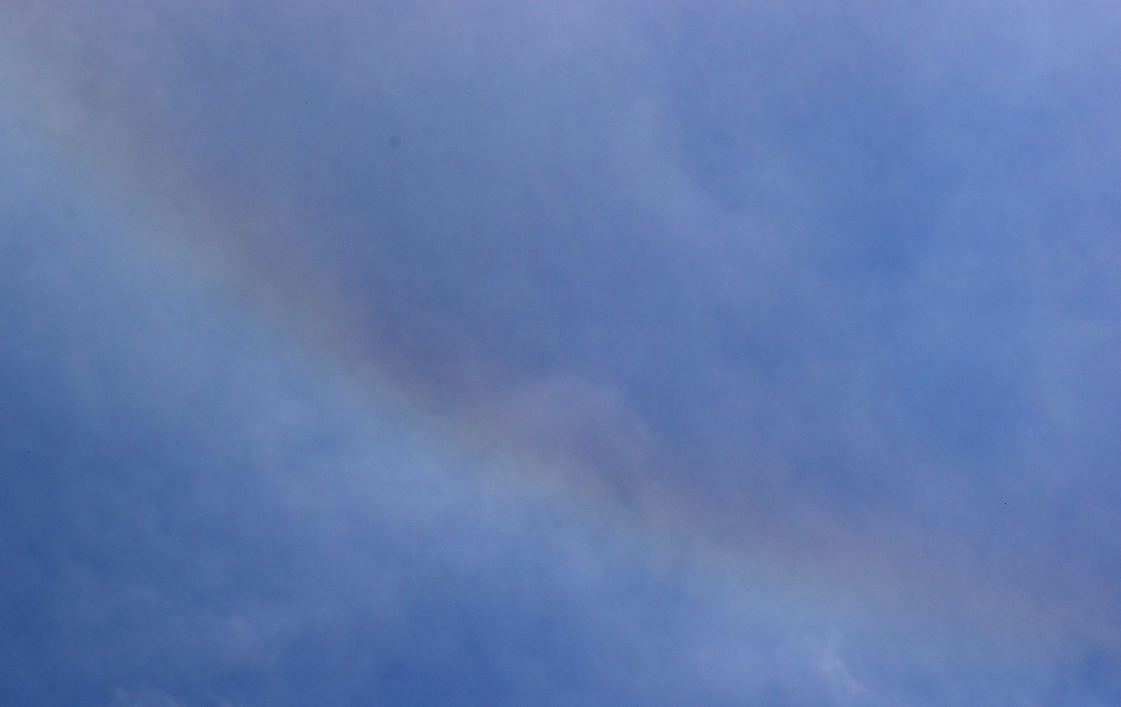 Pelangi halus melengkung di langit biru