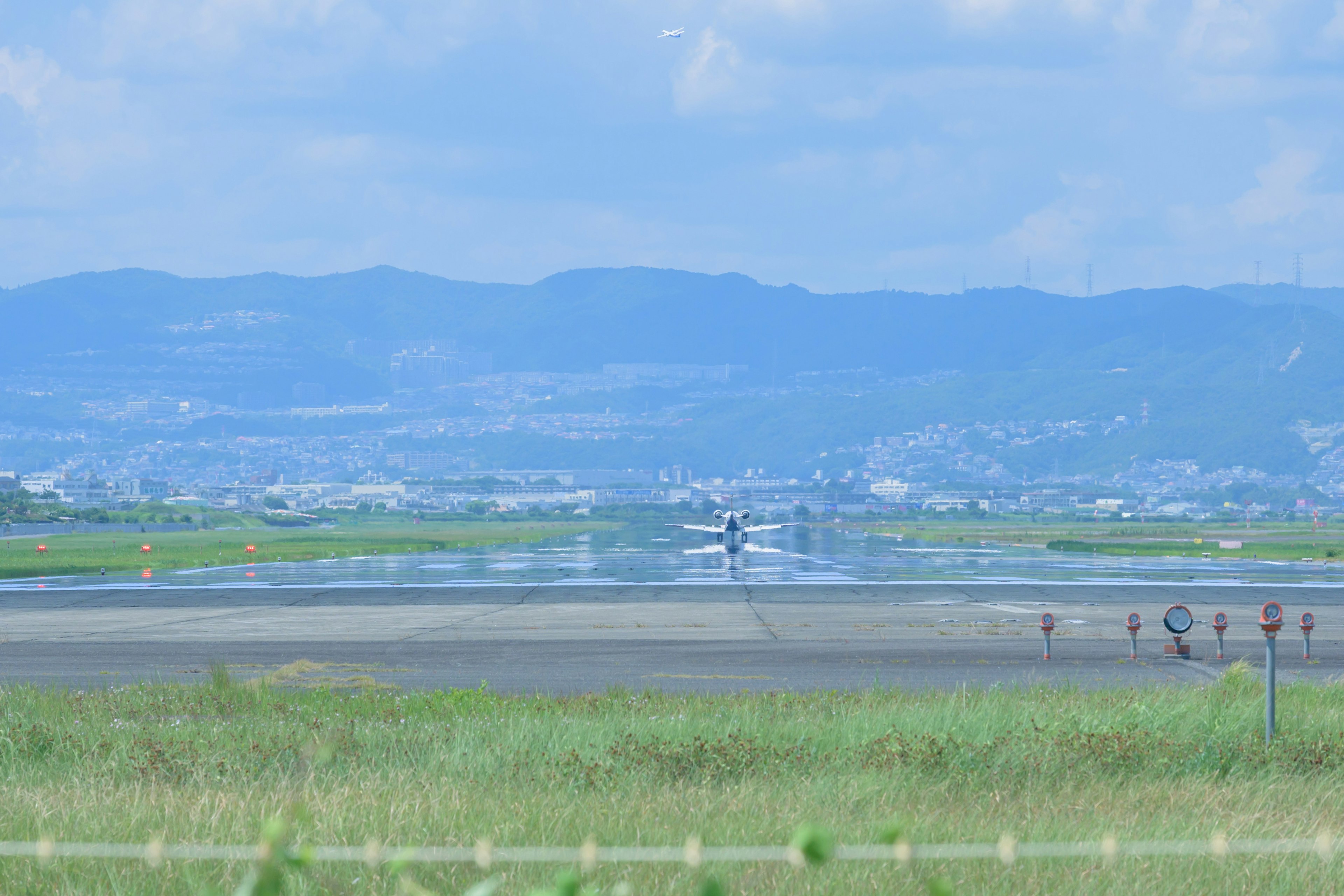 Small aircraft taking off on a runway under a blue sky with green grass