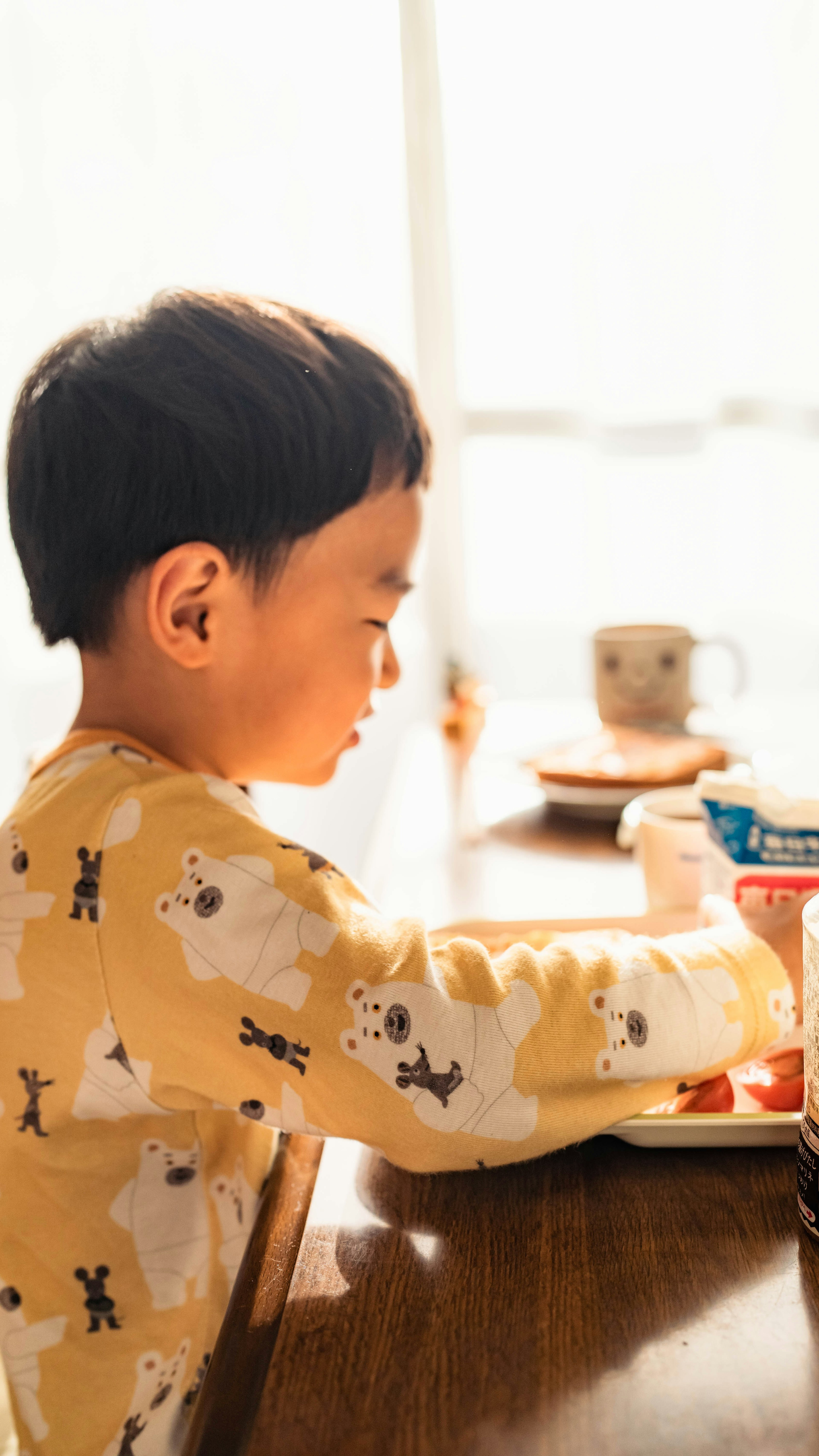 Child enjoying snacks by the window wearing cute animal pajamas