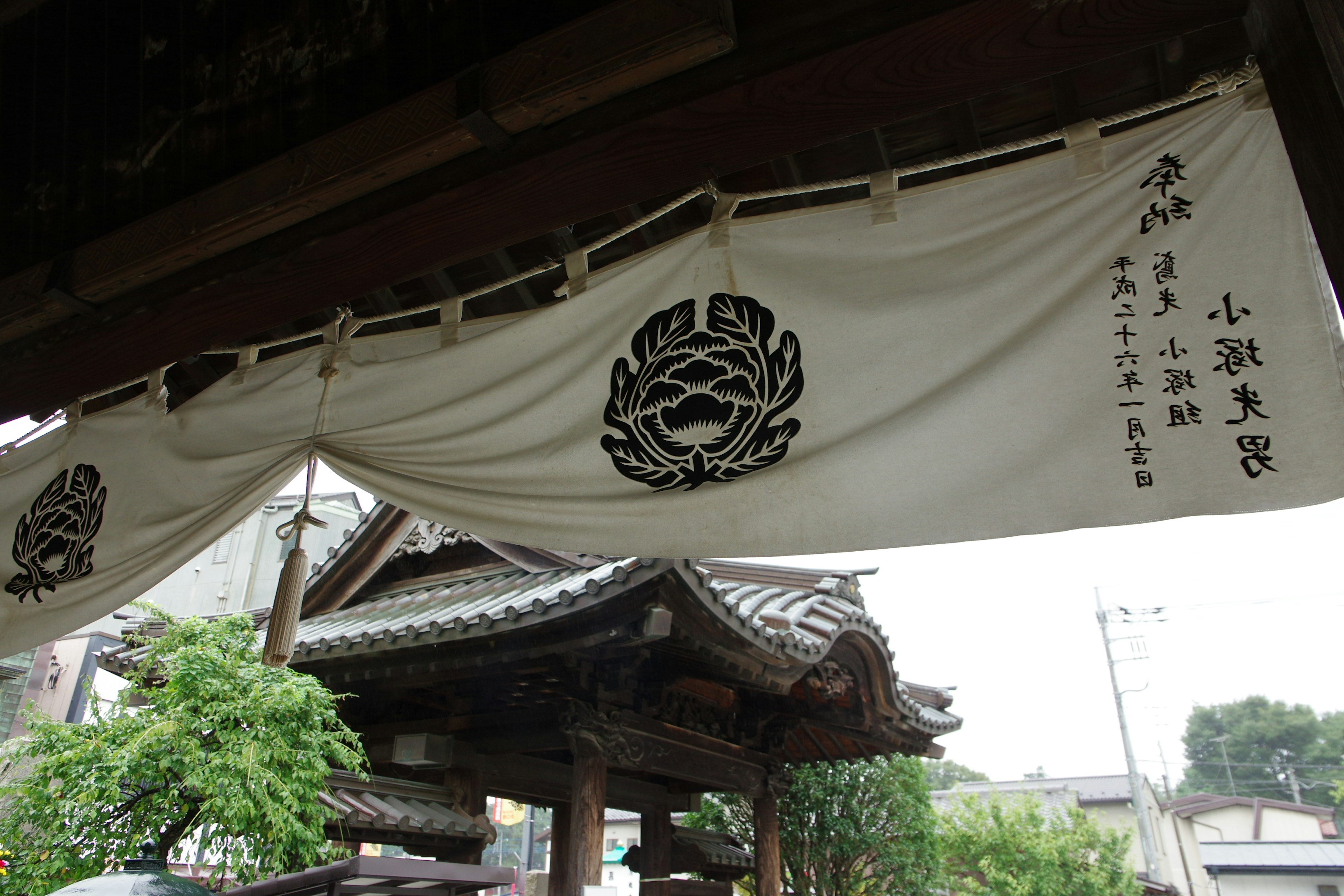 Traditional Japanese building entrance featuring a white noren with flower patterns and text