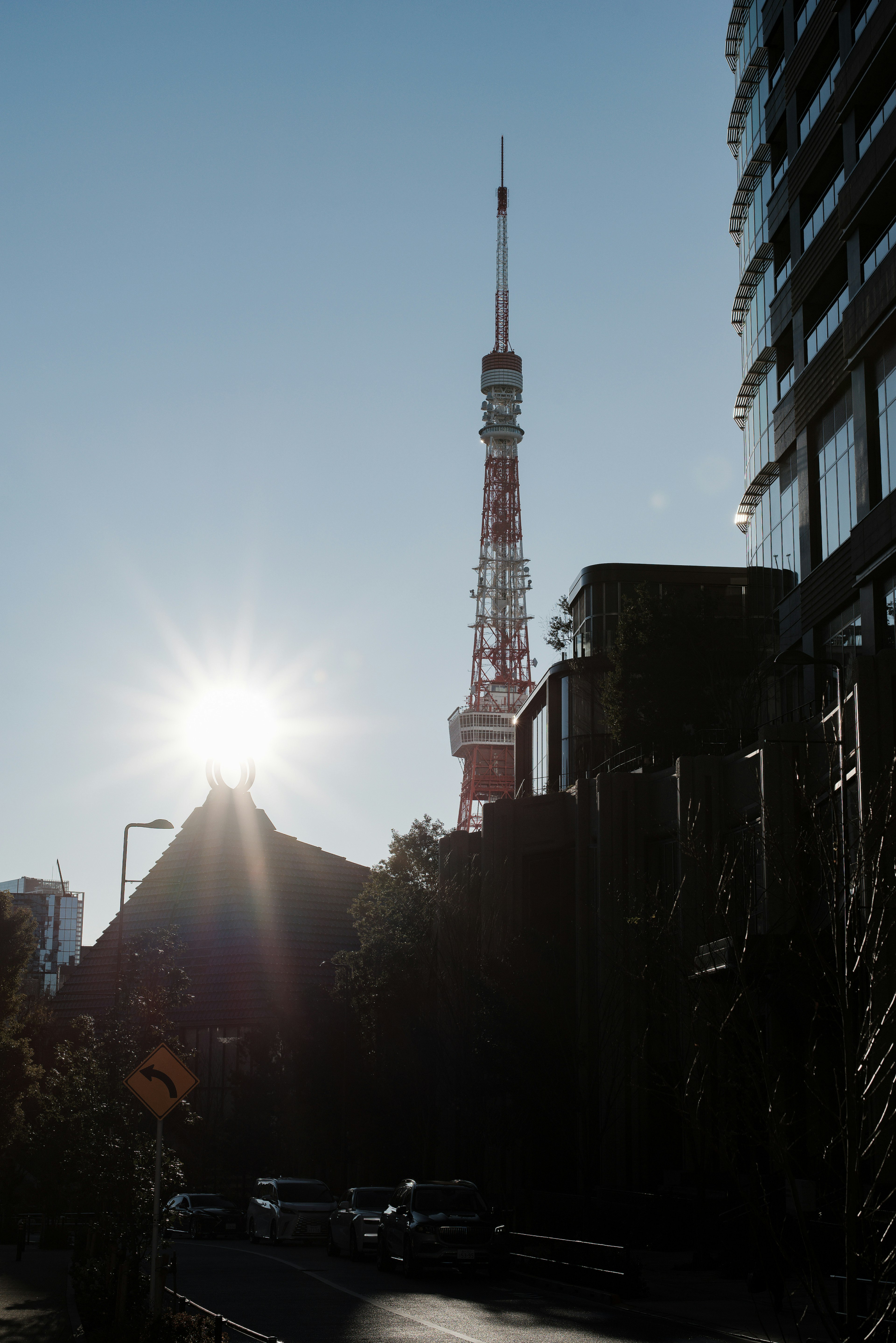 Silhouette de la Tour de Tokyo contre le soleil avec des bâtiments environnants et une rue