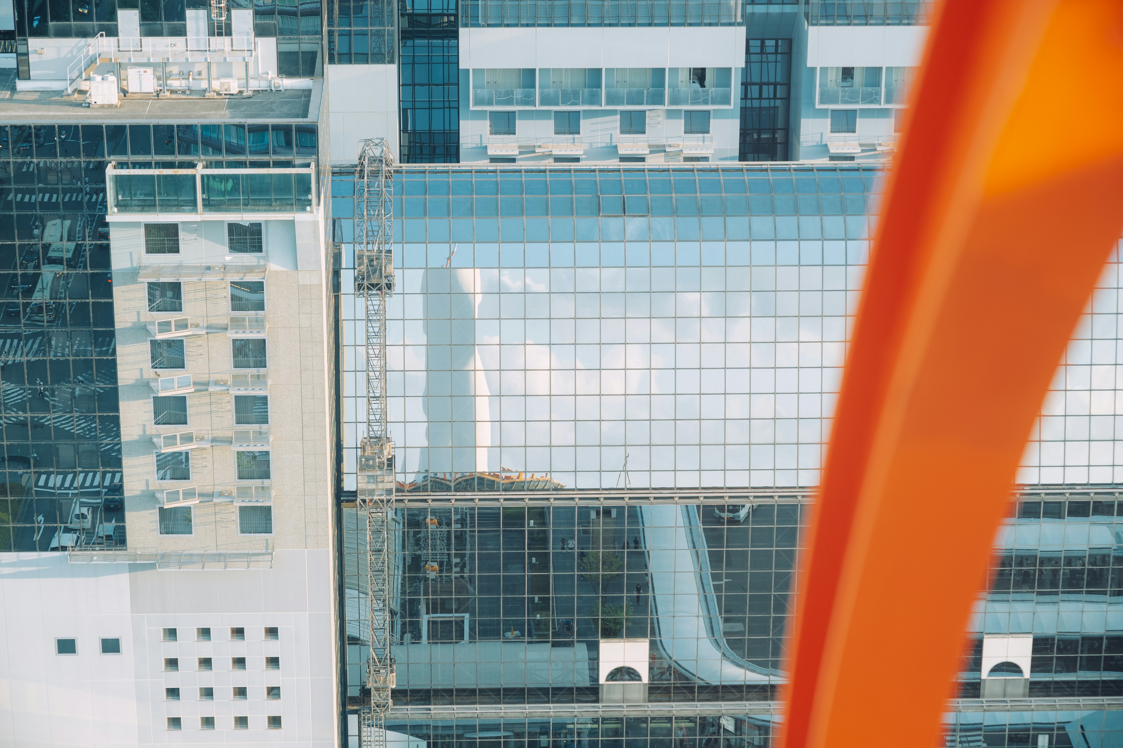 Aerial view of urban buildings featuring glass structures and an orange framework