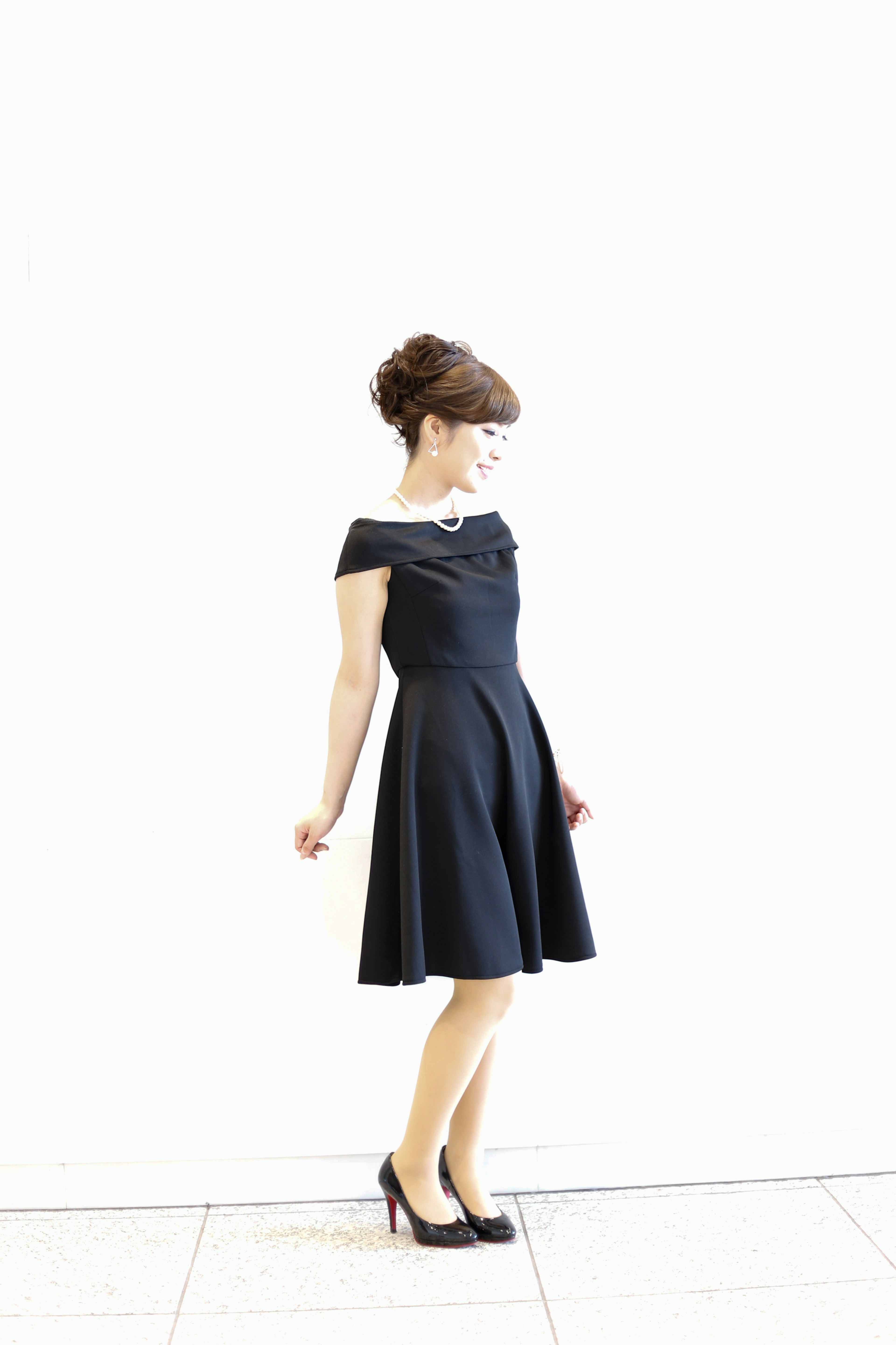 A woman in a black dress standing against a simple background