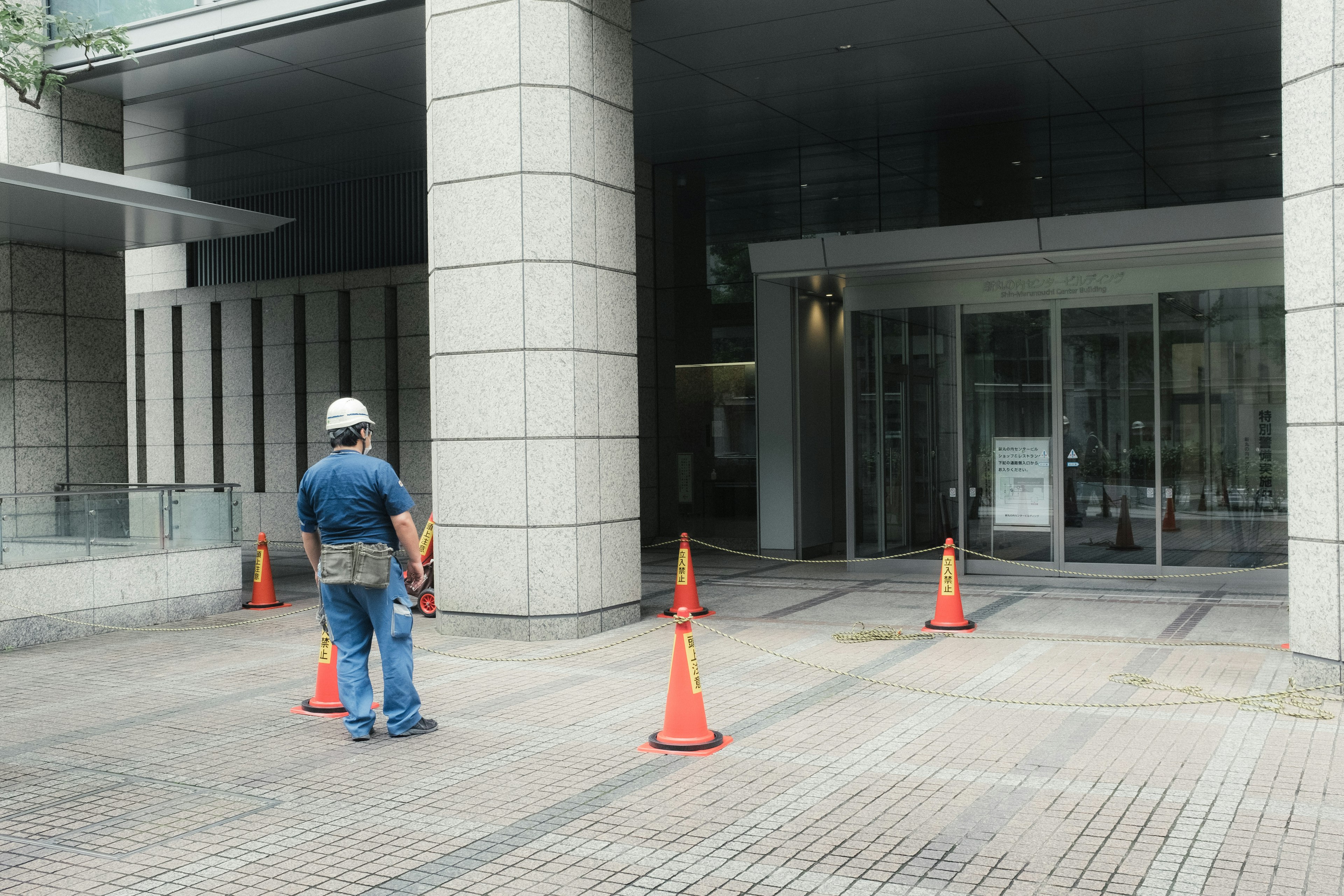 Ouvrier de construction se tenant près de cônes orange à l'entrée d'un bâtiment