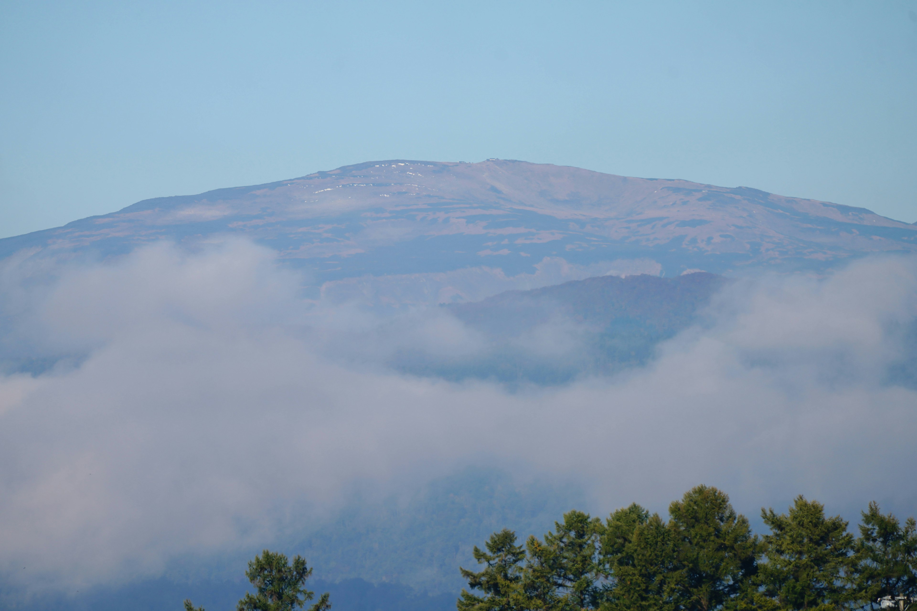 Montaña que se eleva sobre las nubes en un cielo despejado