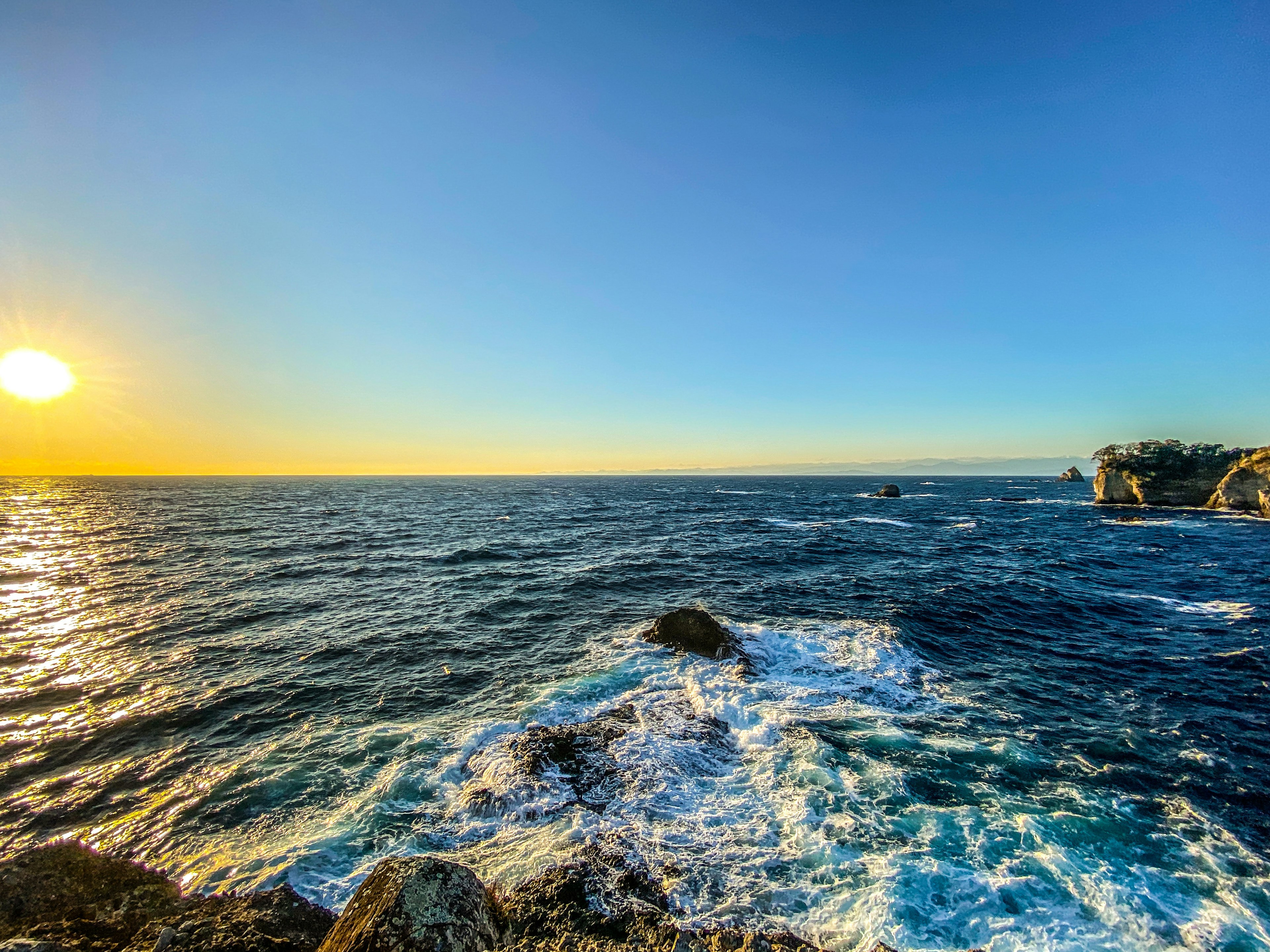 Coucher de soleil sur l'océan avec des vagues frappant la côte rocheuse