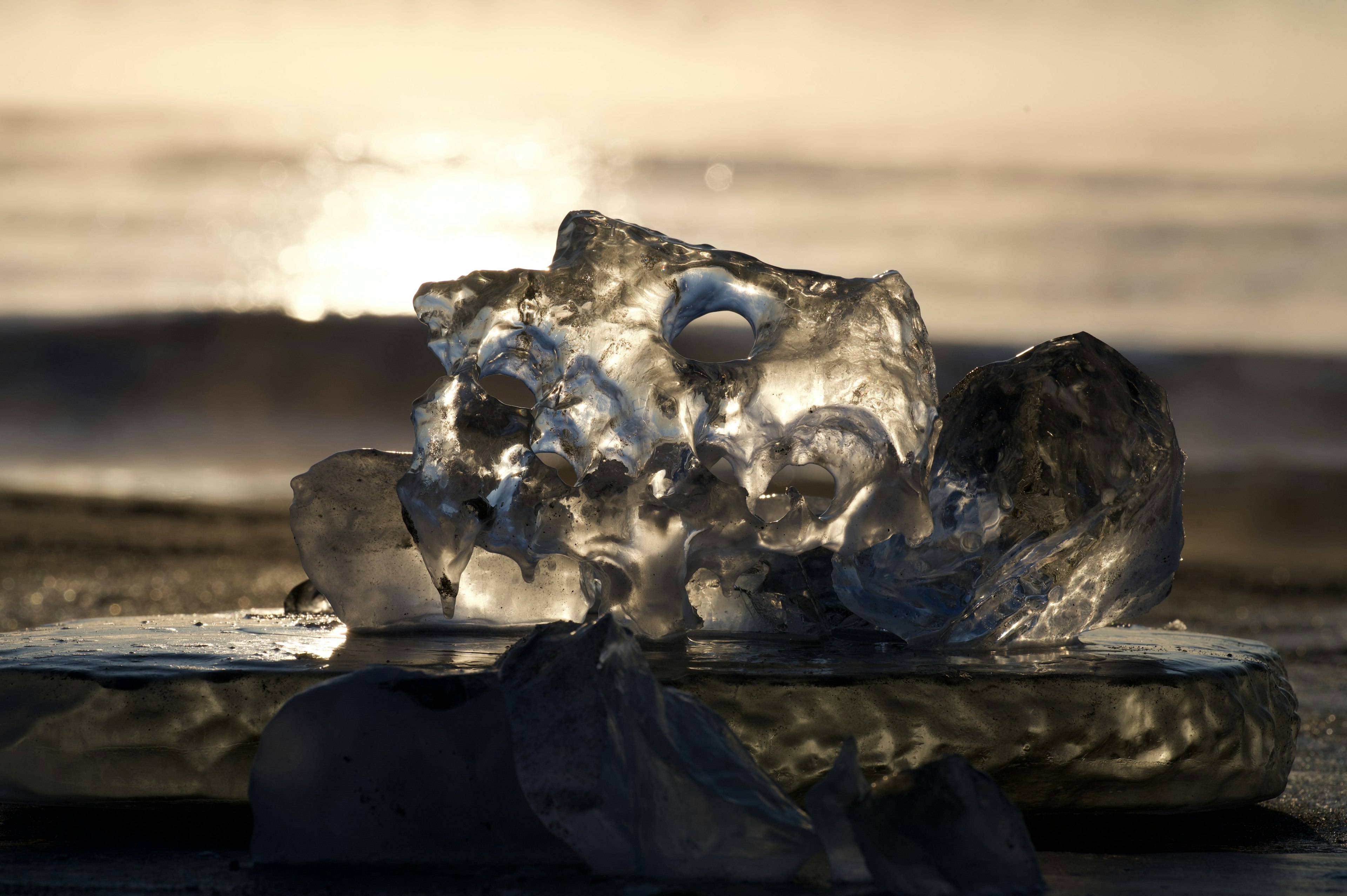 Un trozo de hielo transparente en la playa reflejando la puesta de sol