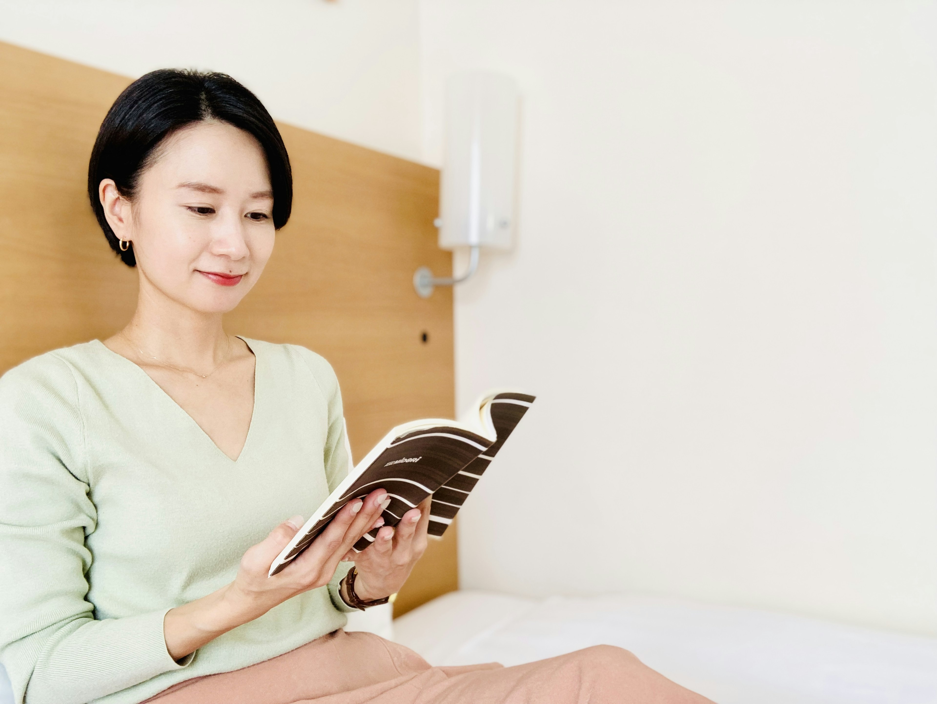 Woman sitting on a bed reading a book