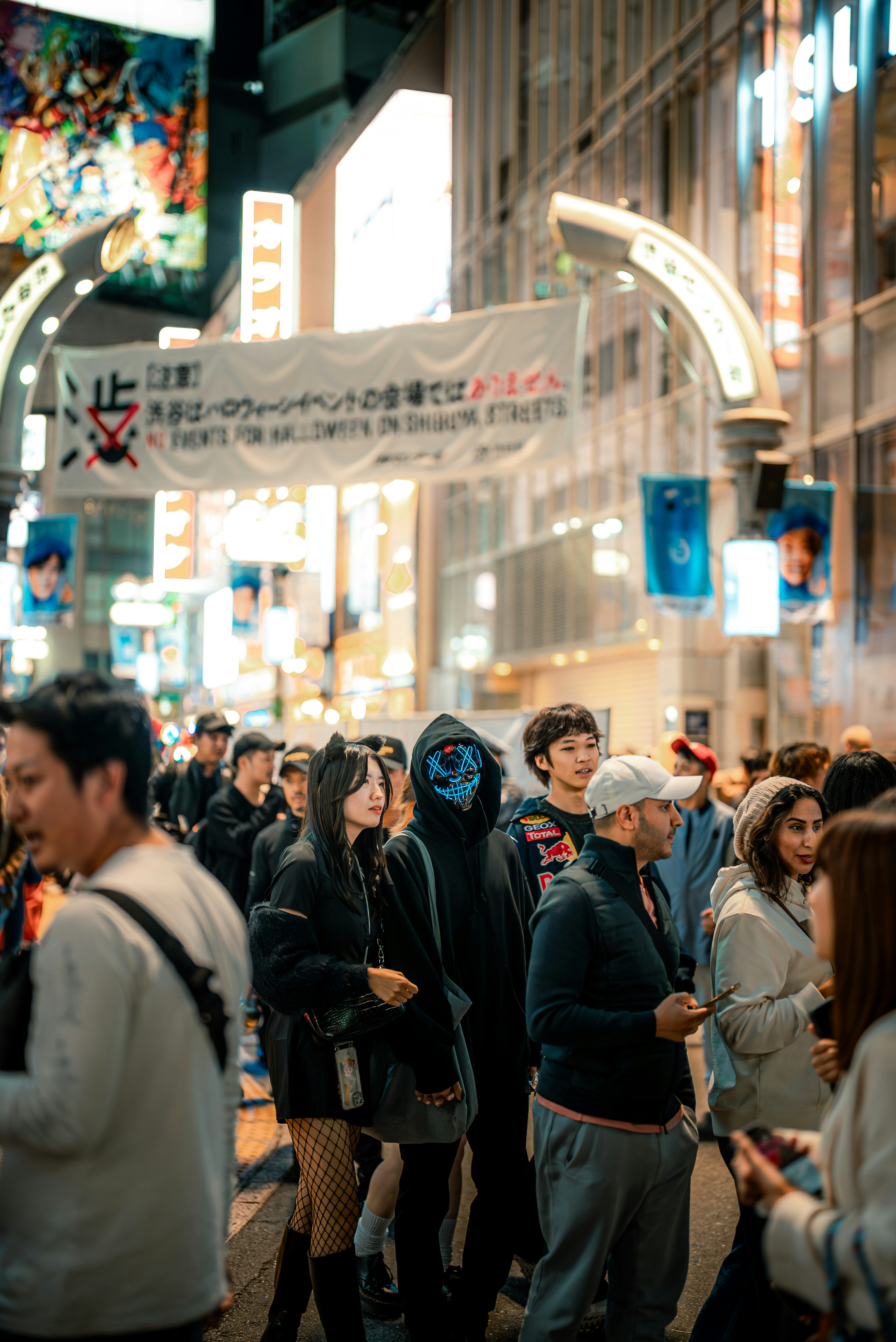 Crowd of people holding smartphones on a busy street with neon signs