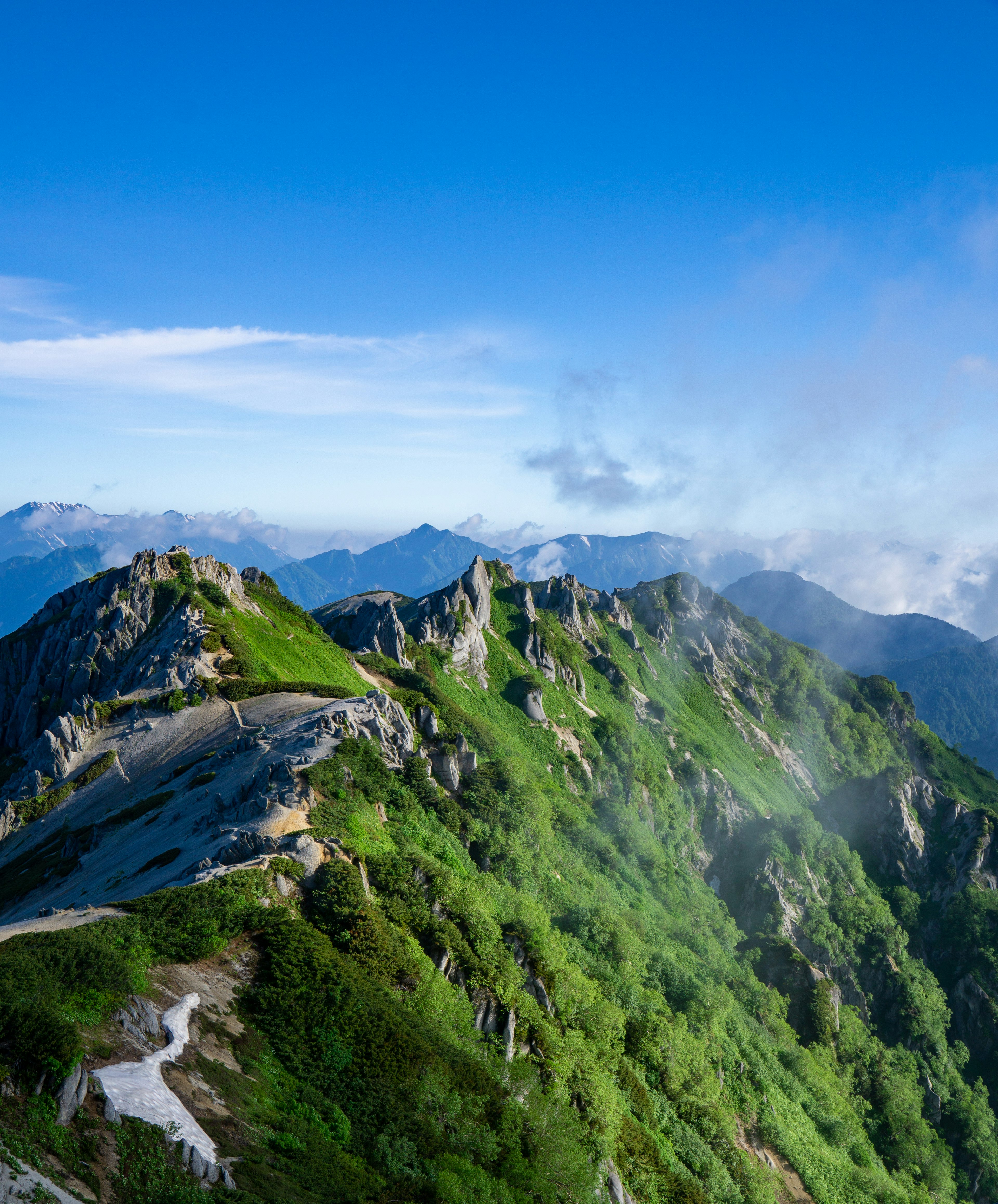 Lush green mountain landscape surrounded by blue sky and clouds