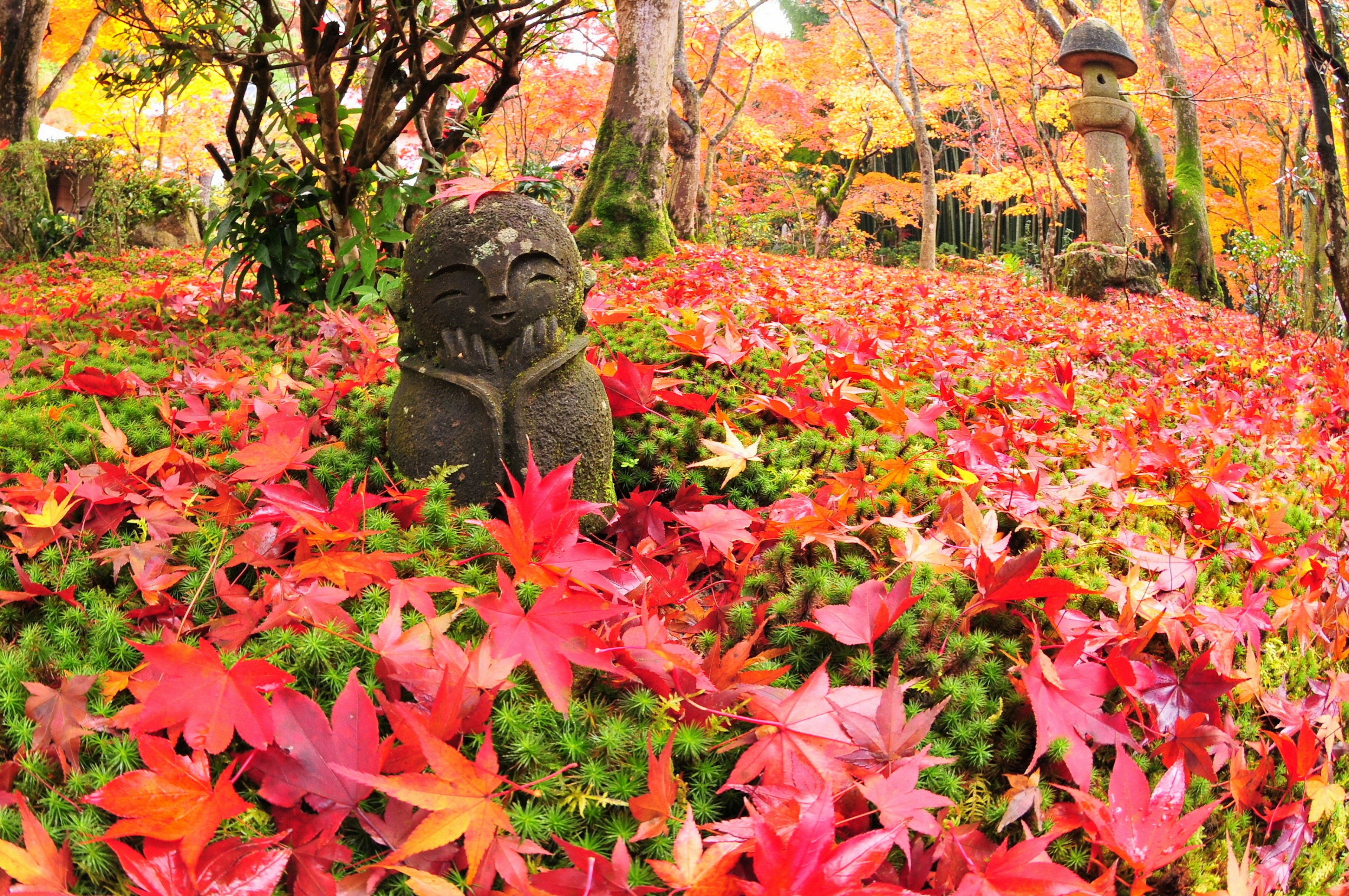 Steinstatue umgeben von lebhaften Herbstblättern in einem Garten