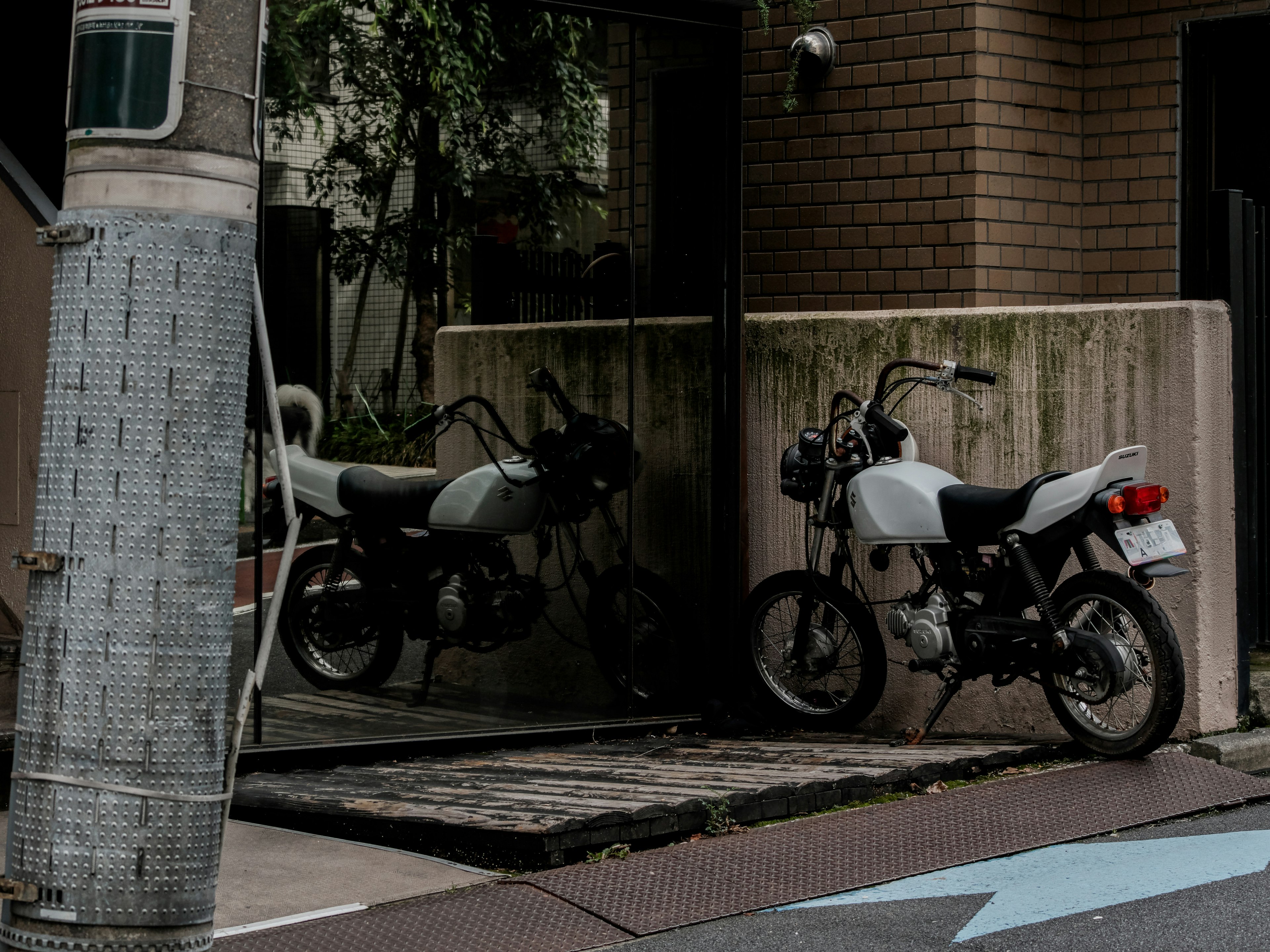 A quiet street corner featuring a white motorcycle and its reflection