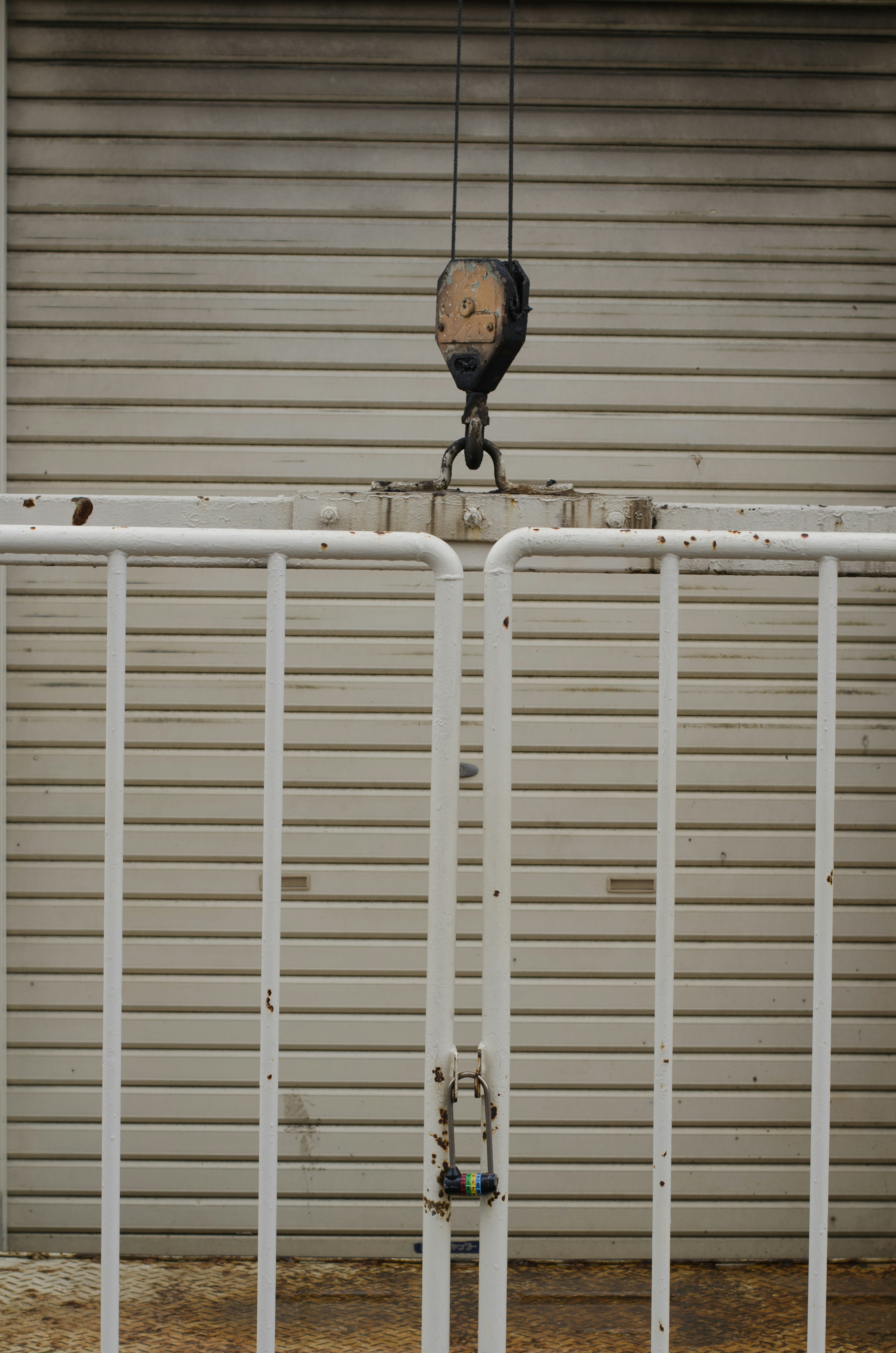 Une clôture blanche avec une grue en bois devant un garage fermé