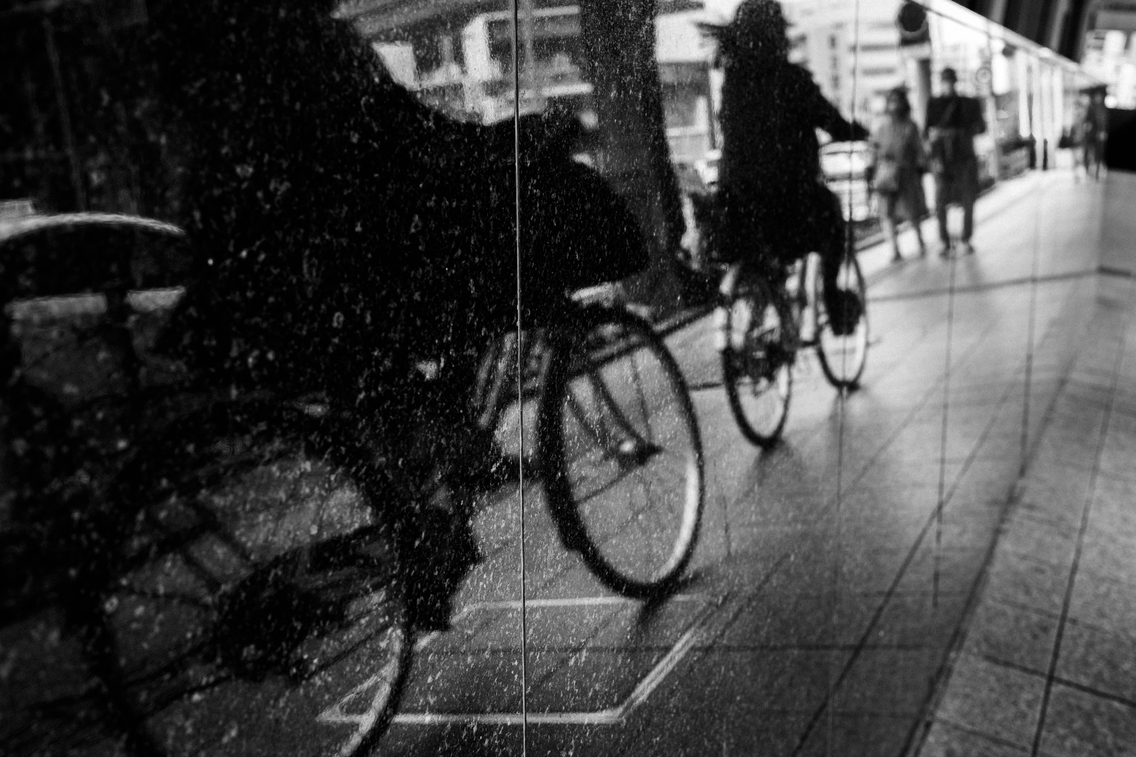 Ombre di persone in bicicletta su una strada di città bagnata