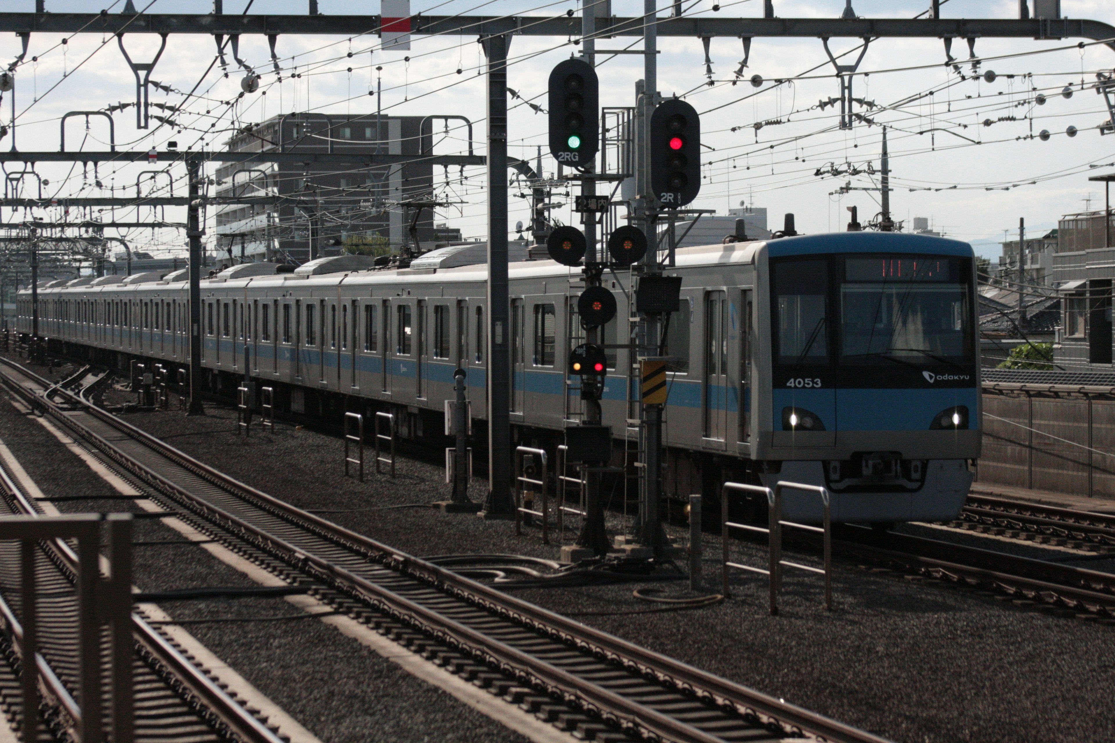 Un tren azul pasando frente a una señal en una estación de tren