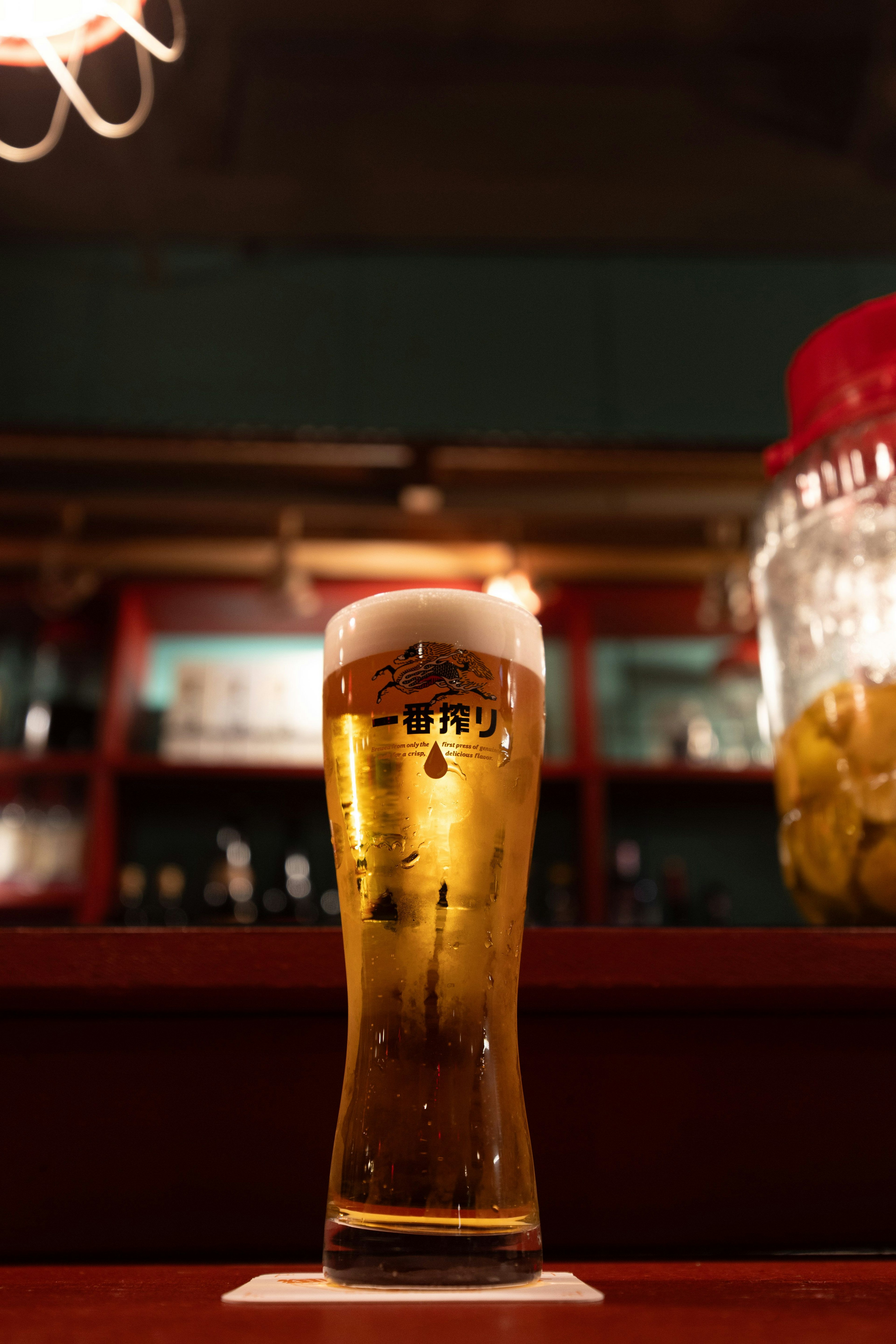 ビールのグラスがカウンターに置かれている背景にぼんやりとしたバーの内部