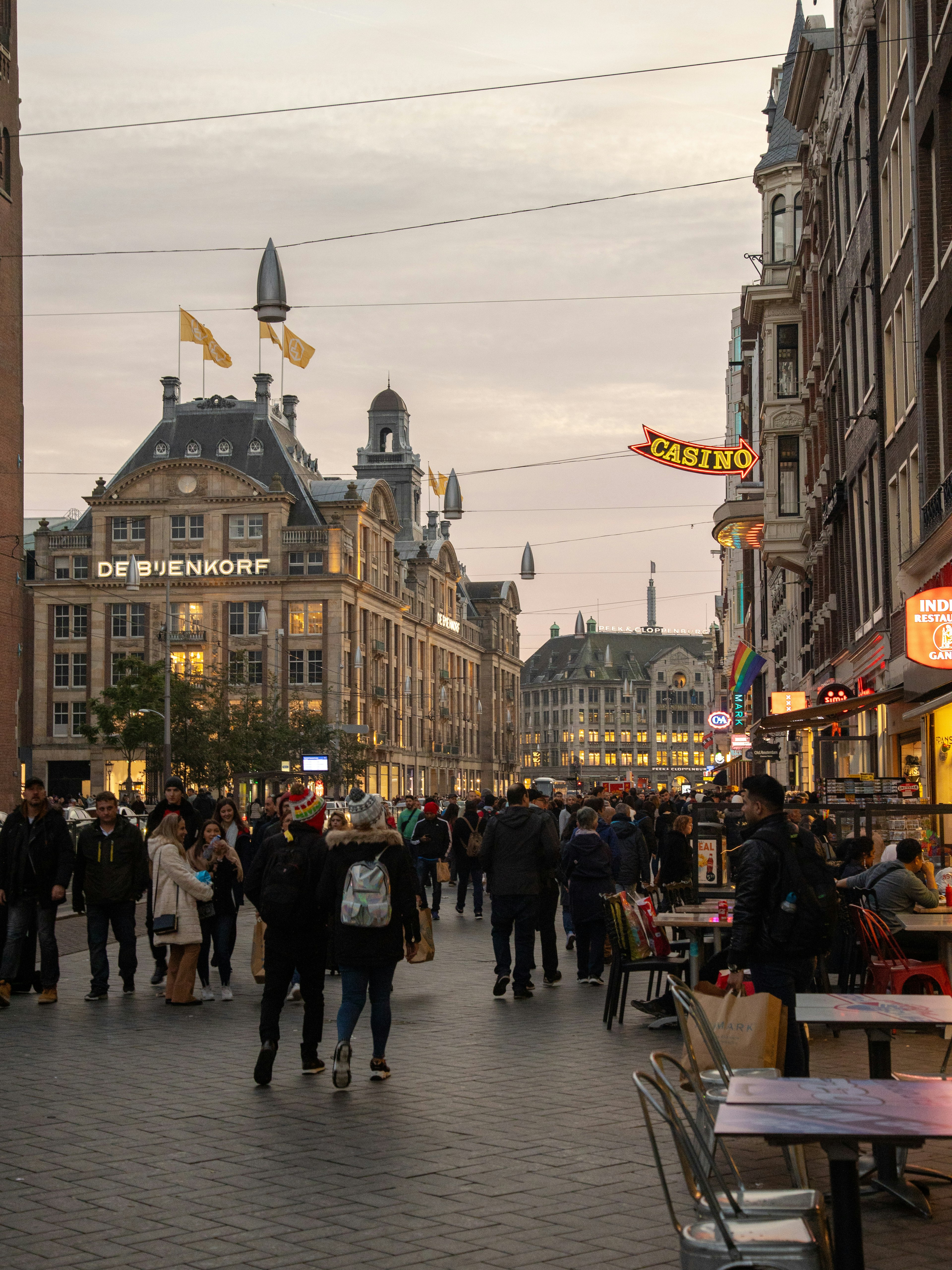 Belebte Straße in Amsterdam bei Dämmerung mit Menschen und historischen Gebäuden