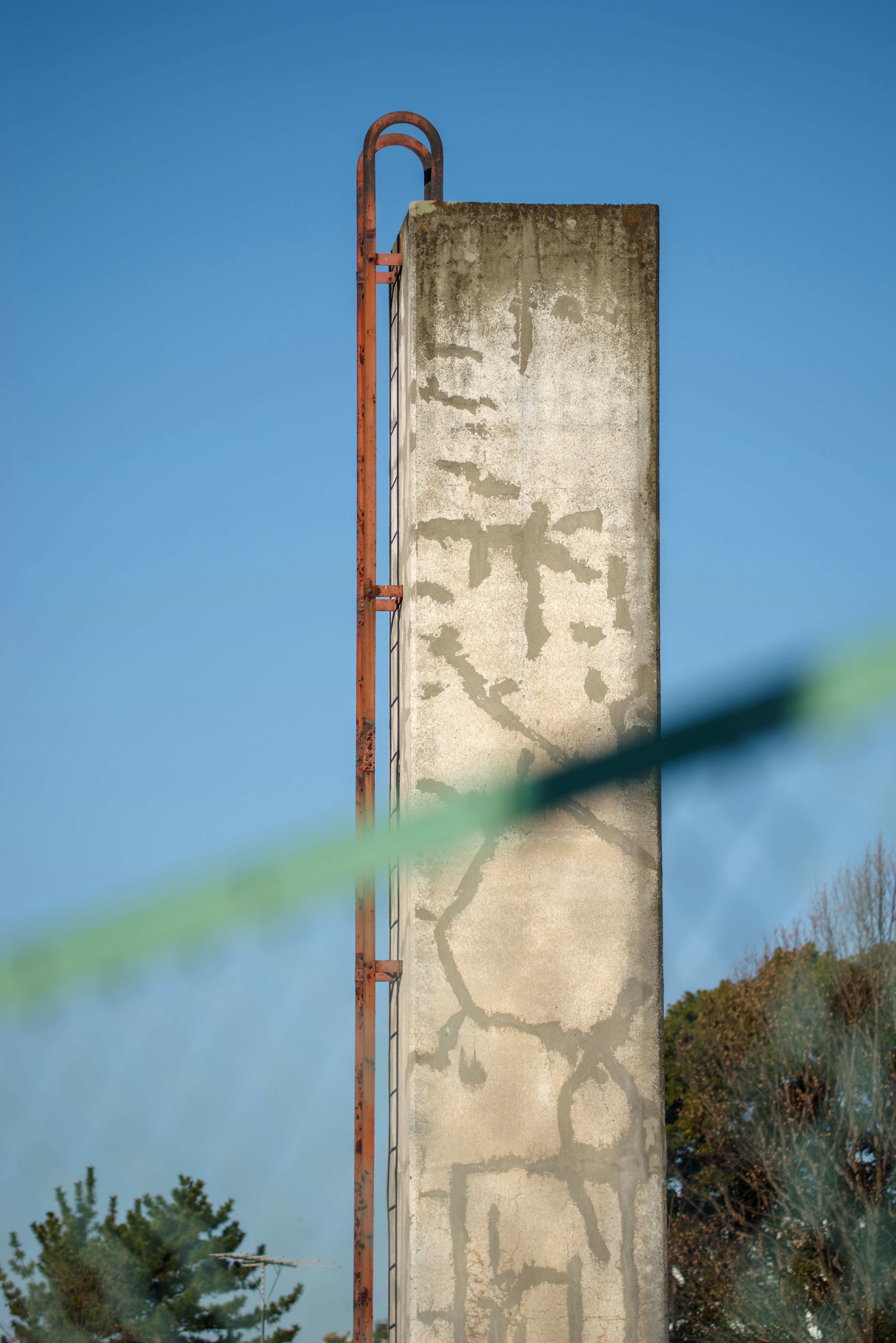 Concrete pillar with rusted pipe against a clear blue sky