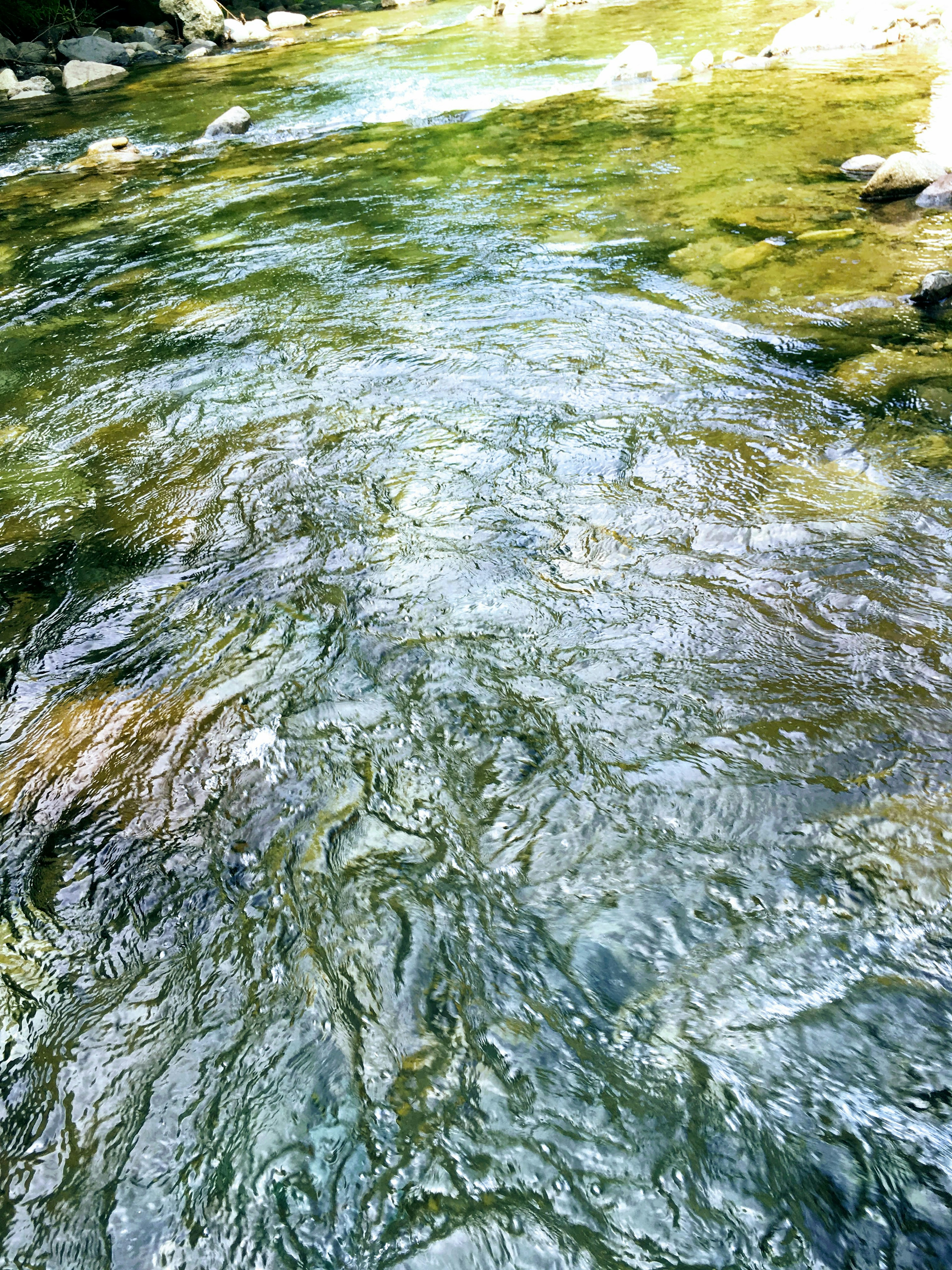 Sungai jernih dengan sinar matahari yang memantul di permukaan air yang beriak