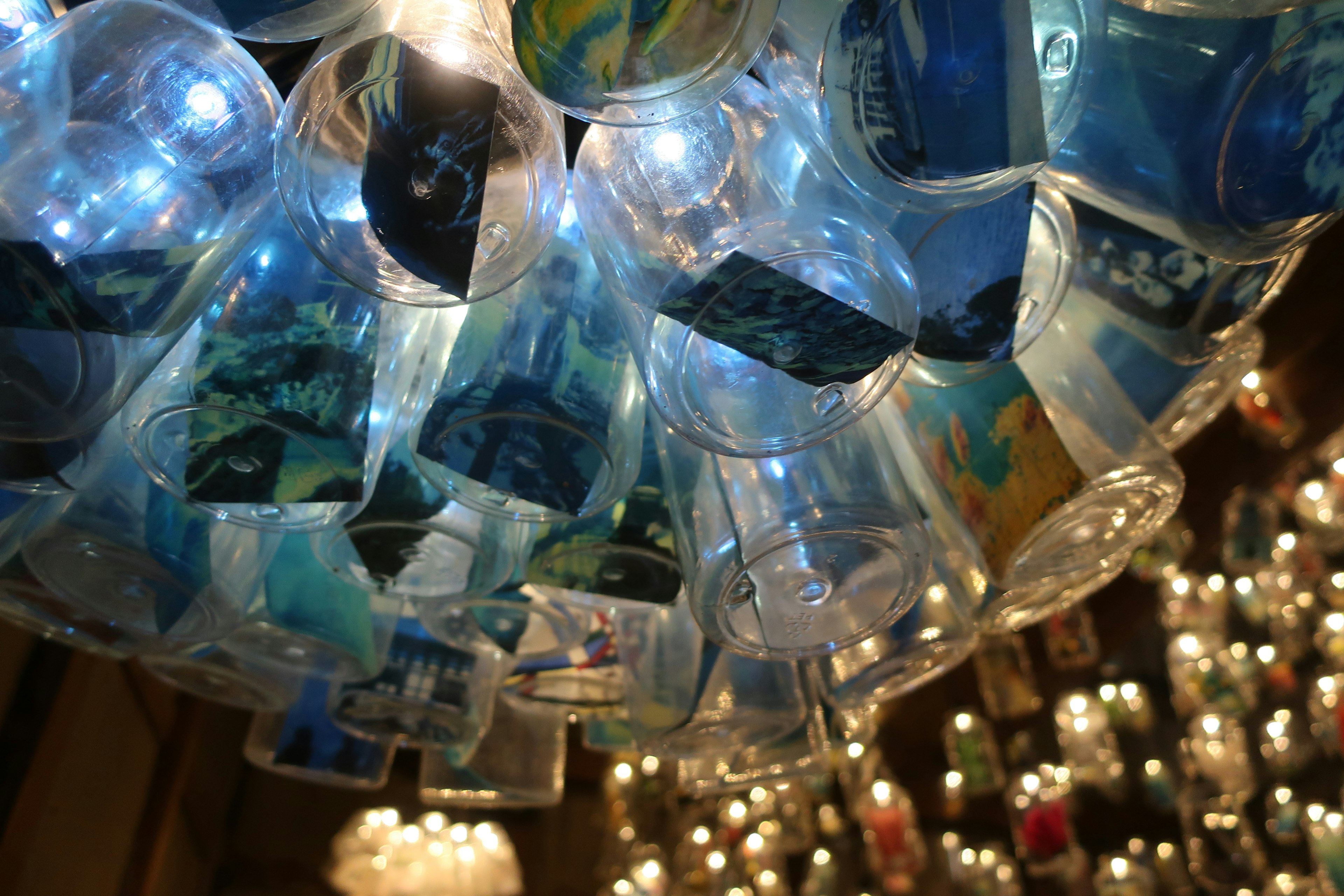 View from below a lamp shade made of illuminated blue cups