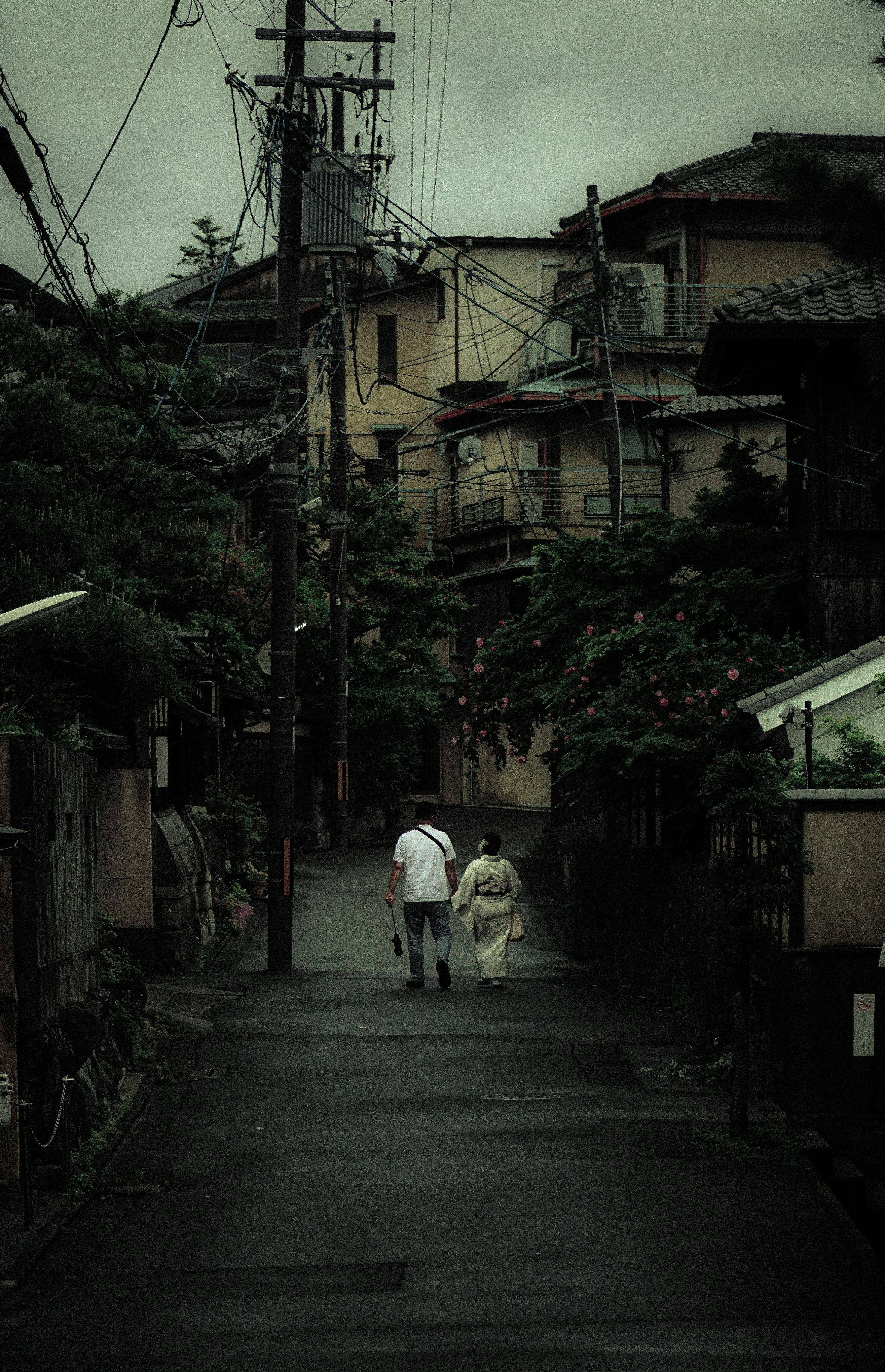 静かな街道を歩く二人の人物と古い家々の風景