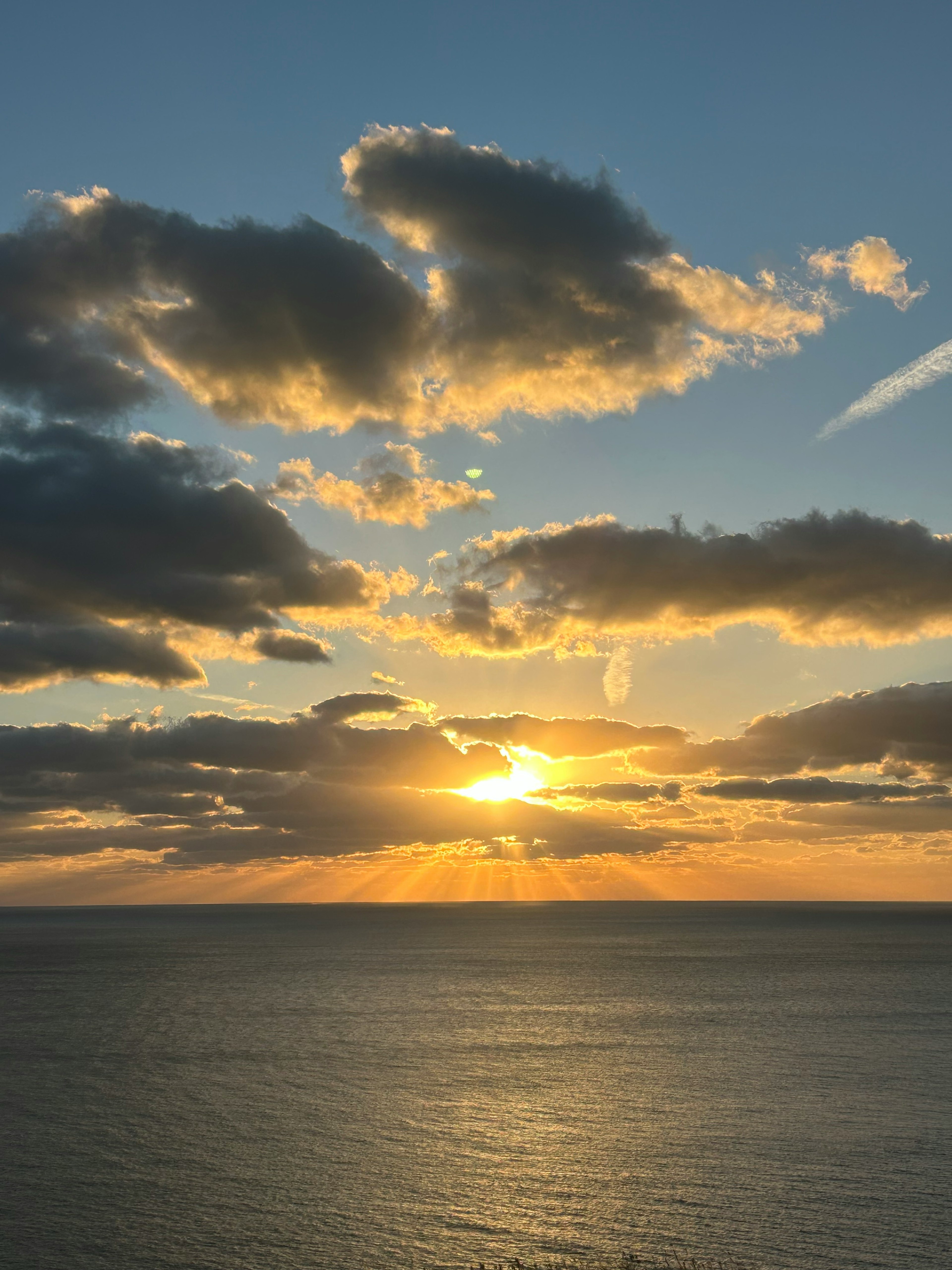 美しい夕日が雲の間から海に沈む情景