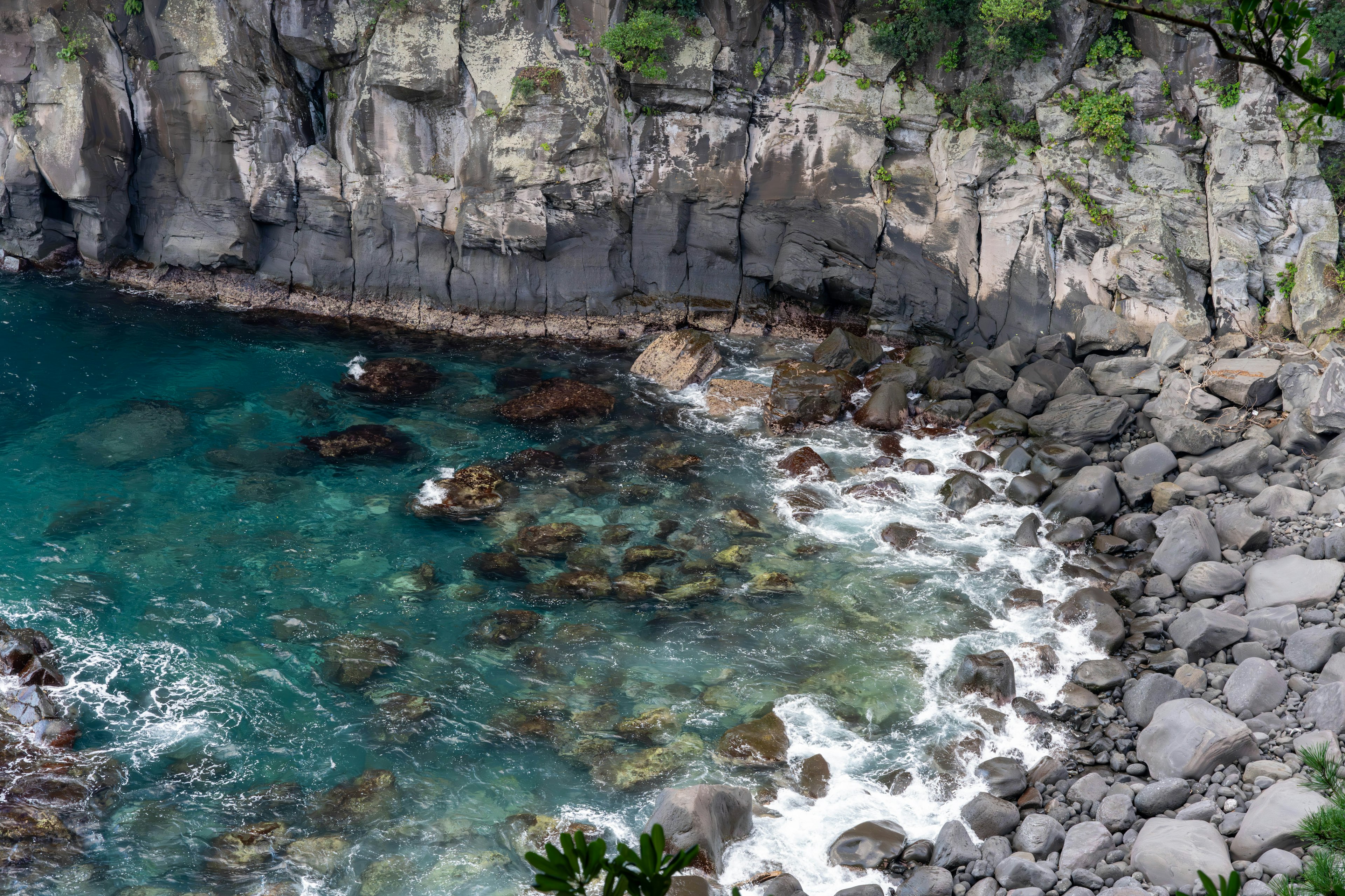 Pemandangan indah air turquoise dan tebing berbatu dengan ombak menghantam