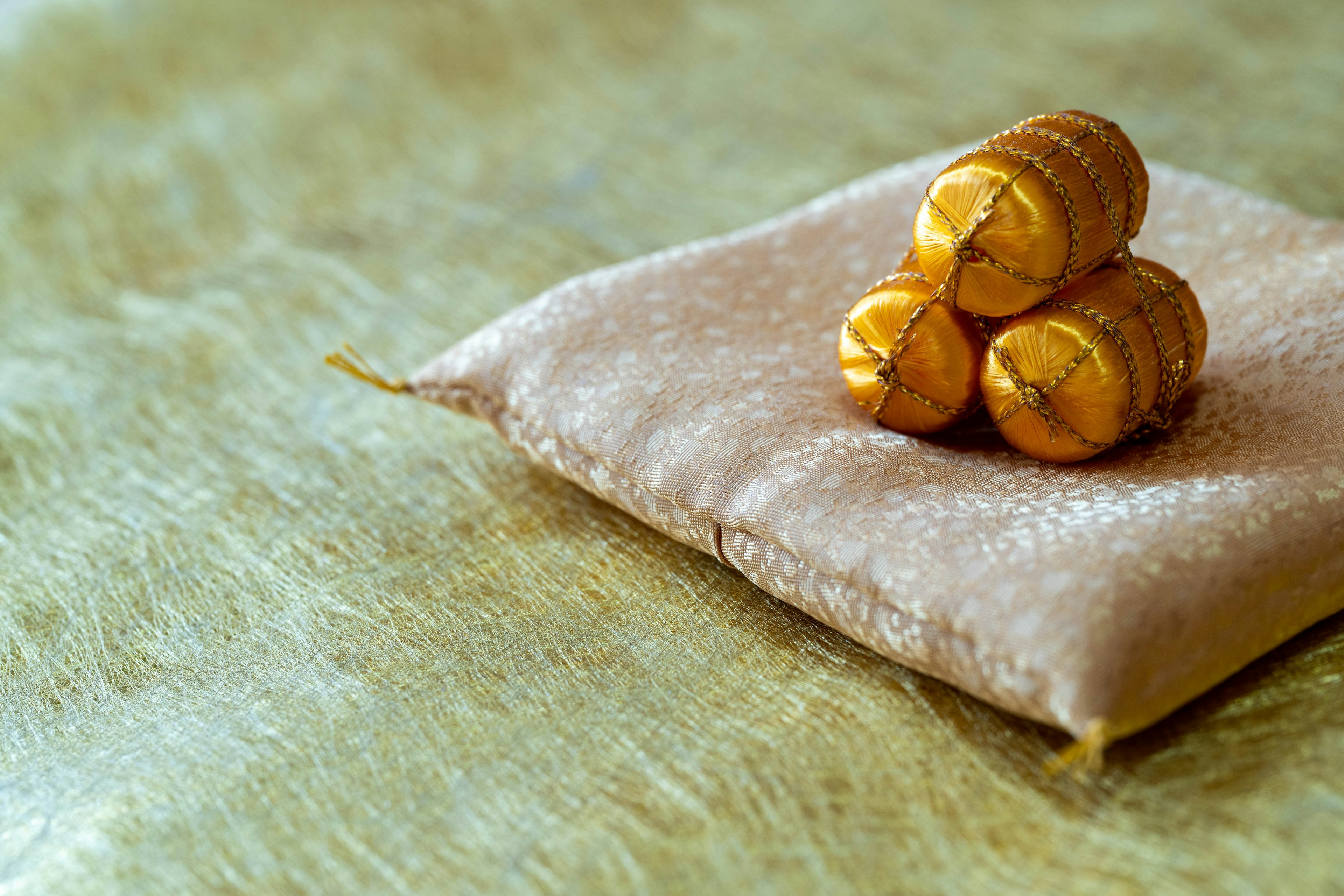 Cojín beige con tres caramelos dorados encima