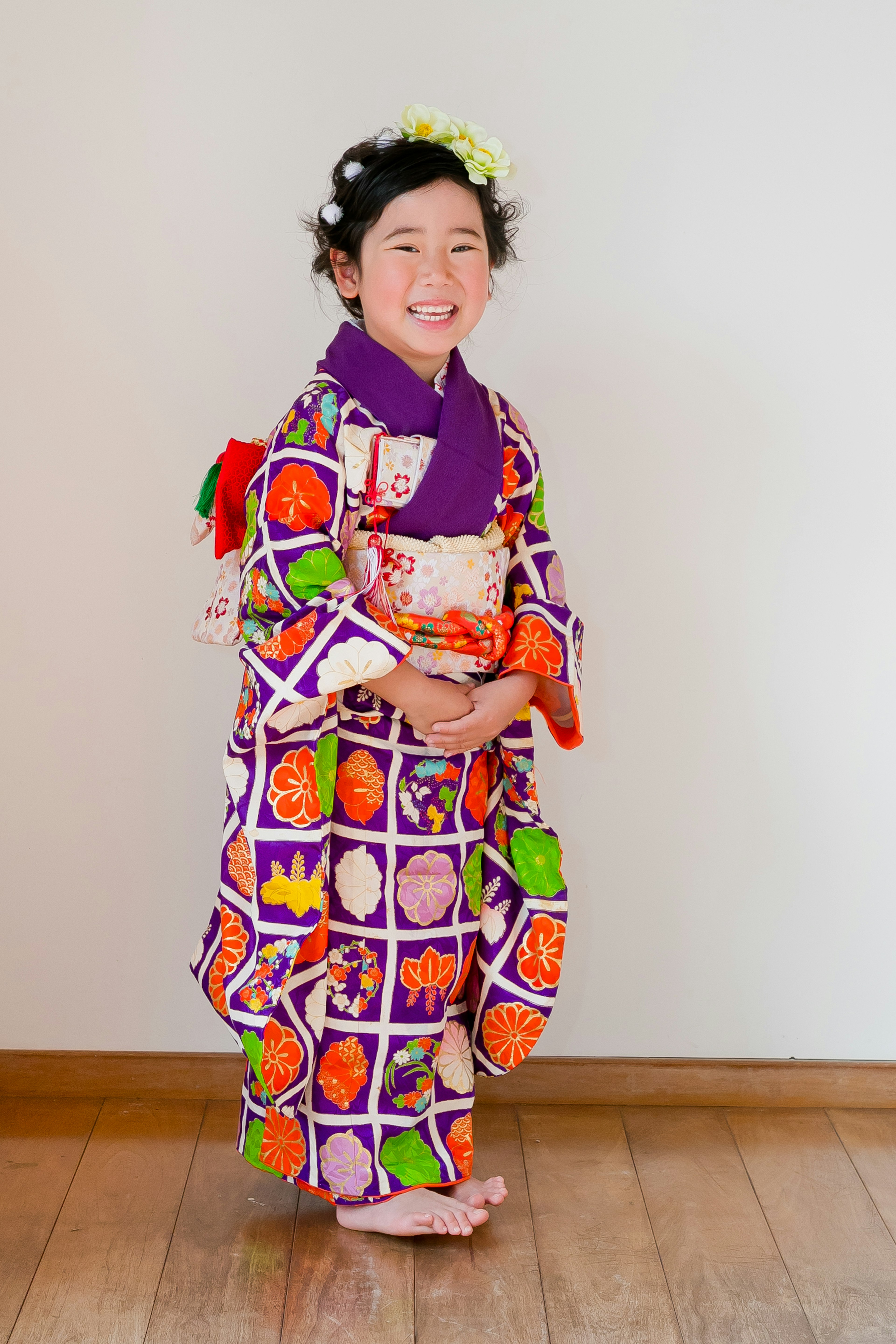 Un niño sonriente vestido con un kimono colorido está de pie frente a un fondo simple