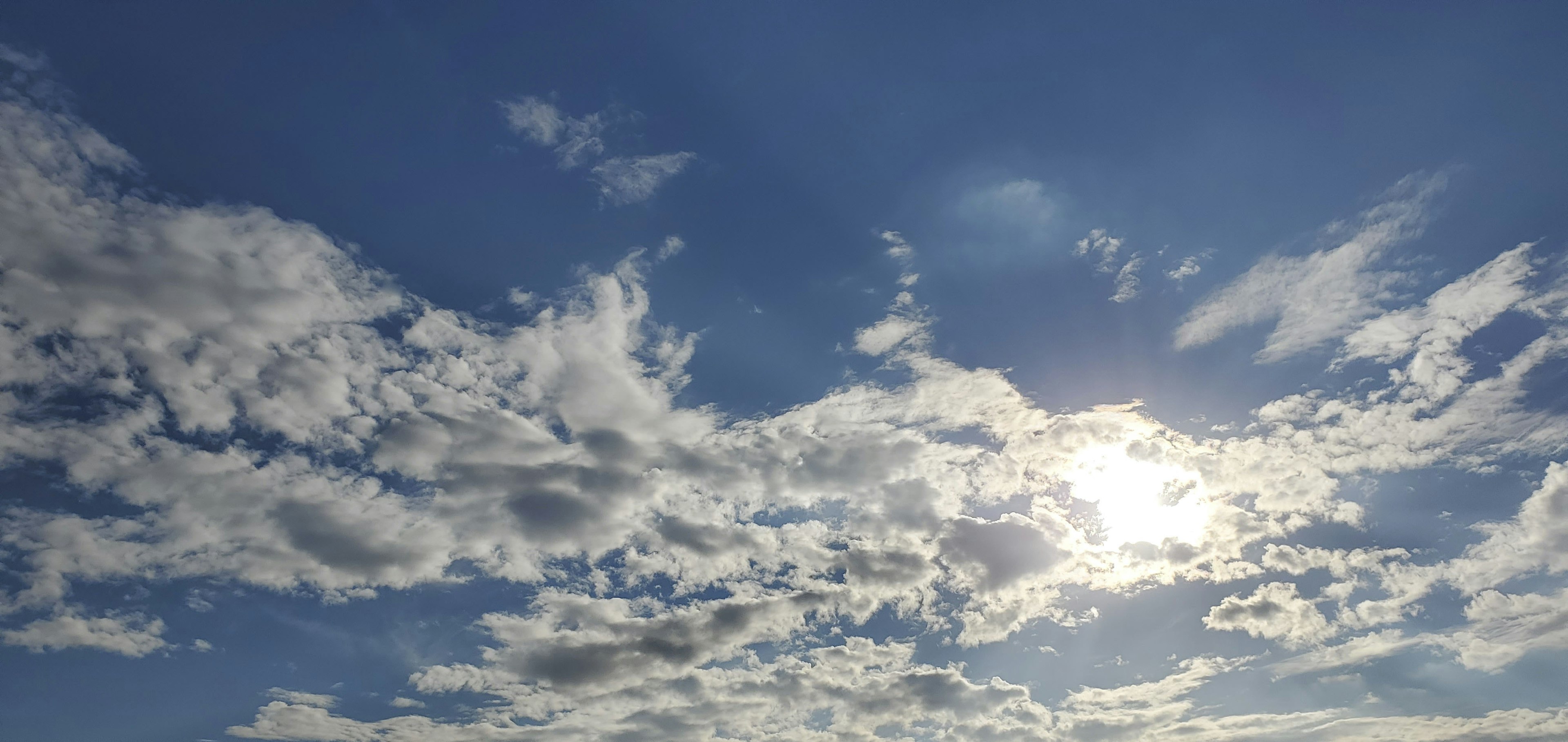 Langit biru dengan awan putih dan sinar matahari menerangi awan