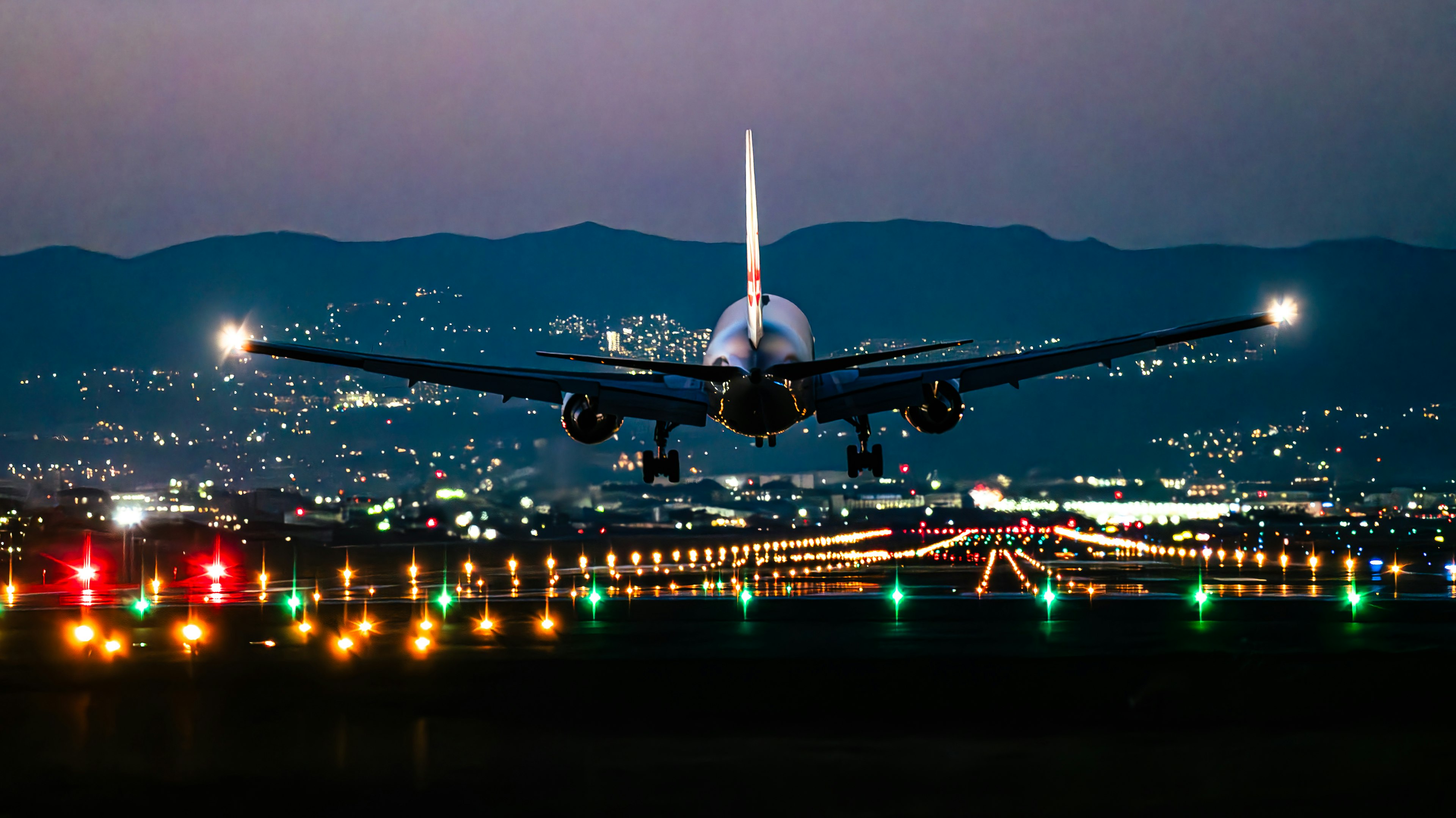 夕暮れ時に着陸する飛行機と明るい空港の滑走路