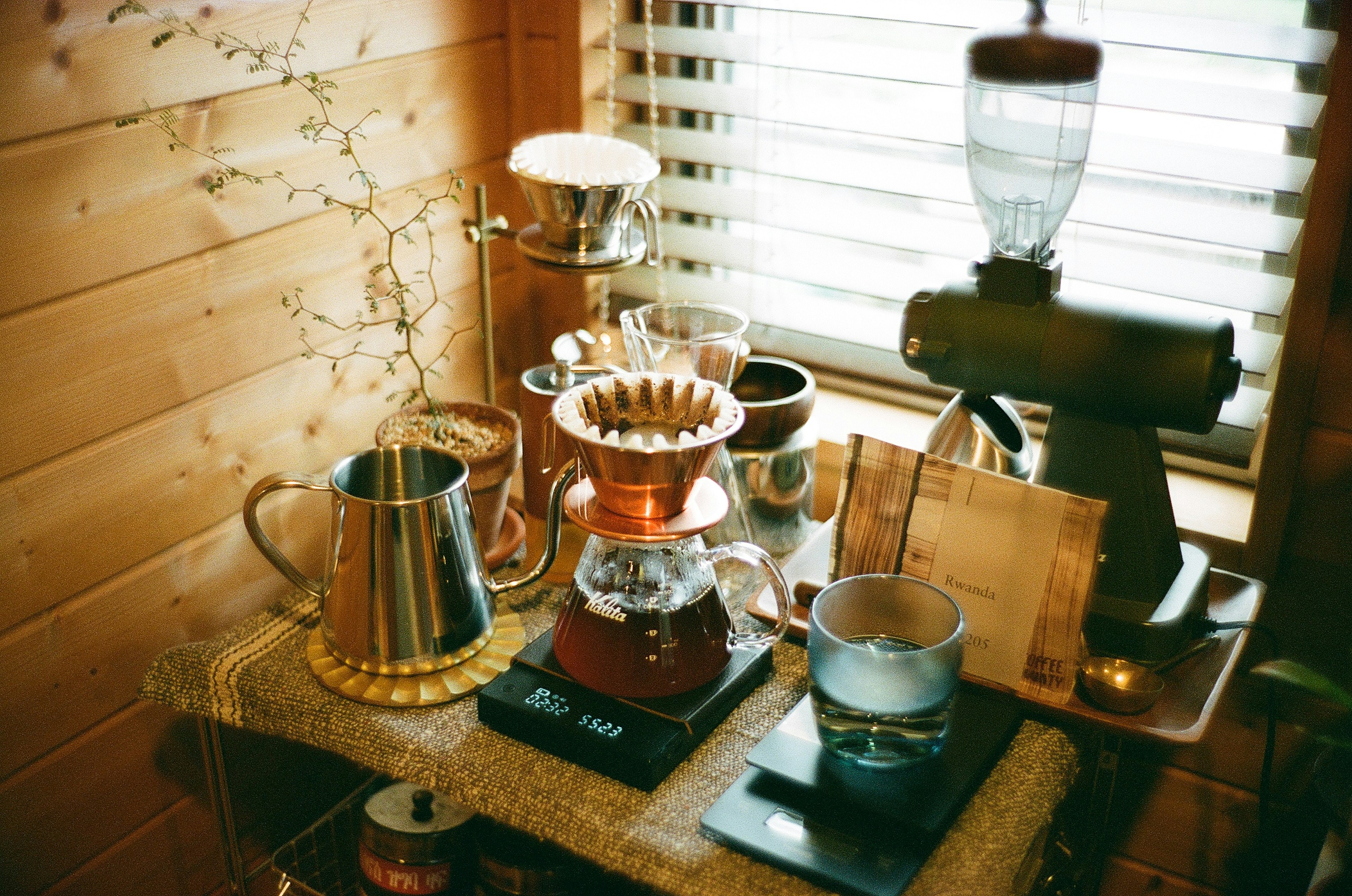 A wooden table displaying various coffee brewing equipment including a coffee server dripper and milk pitcher