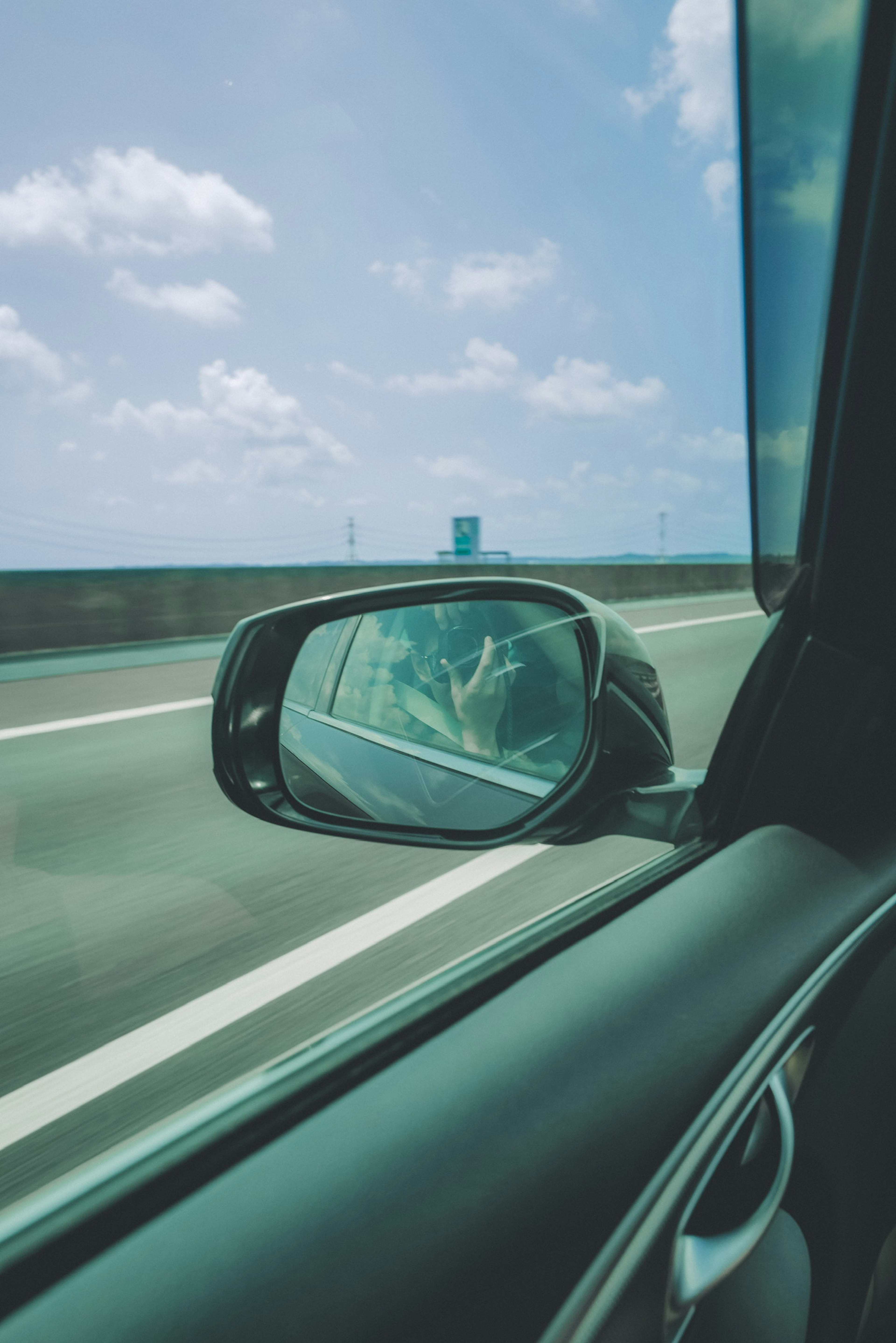 Vue depuis une fenêtre de voiture montrant la route et le reflet du ciel bleu