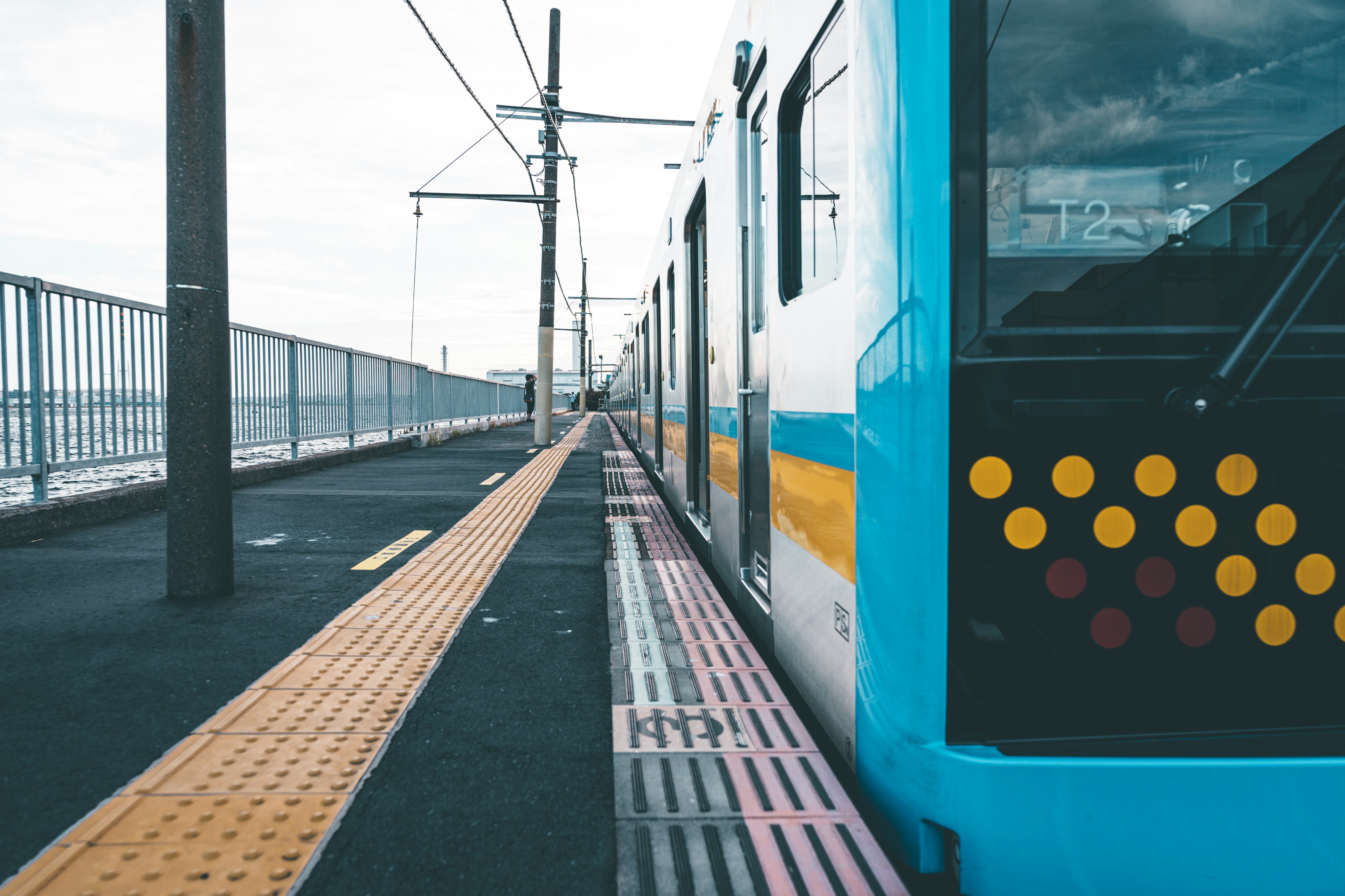 Side view of a blue train at a station platform with colorful dots