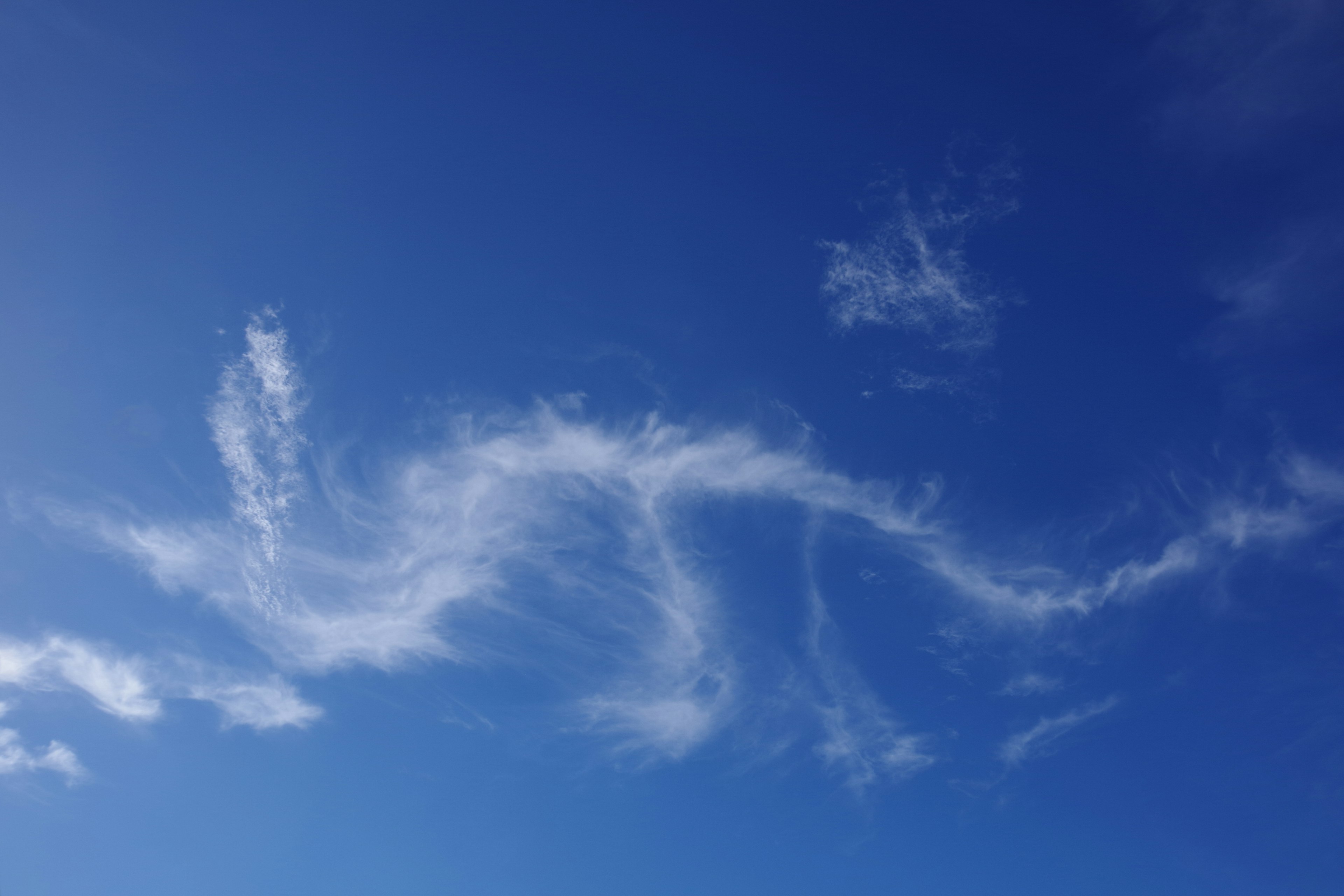 Weiße Wolken im blauen Himmel, die einer Schlange ähneln