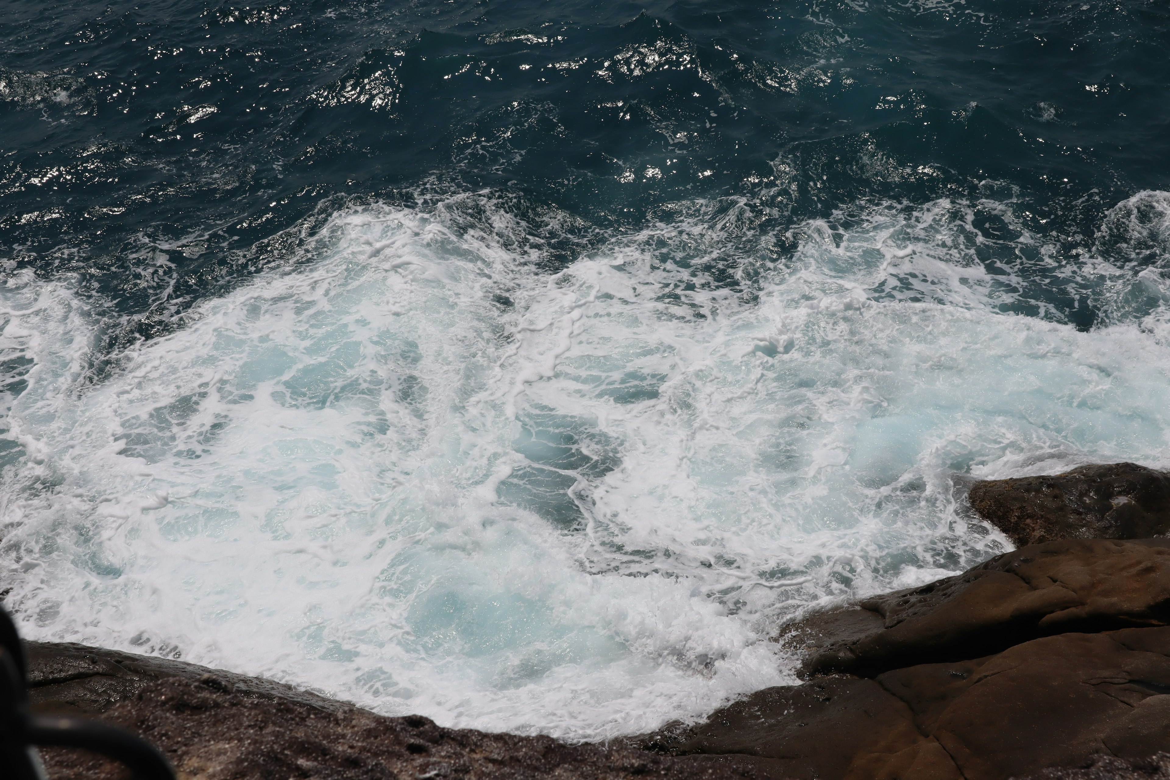 Onde bianche e spumose che si infrangono su rocce